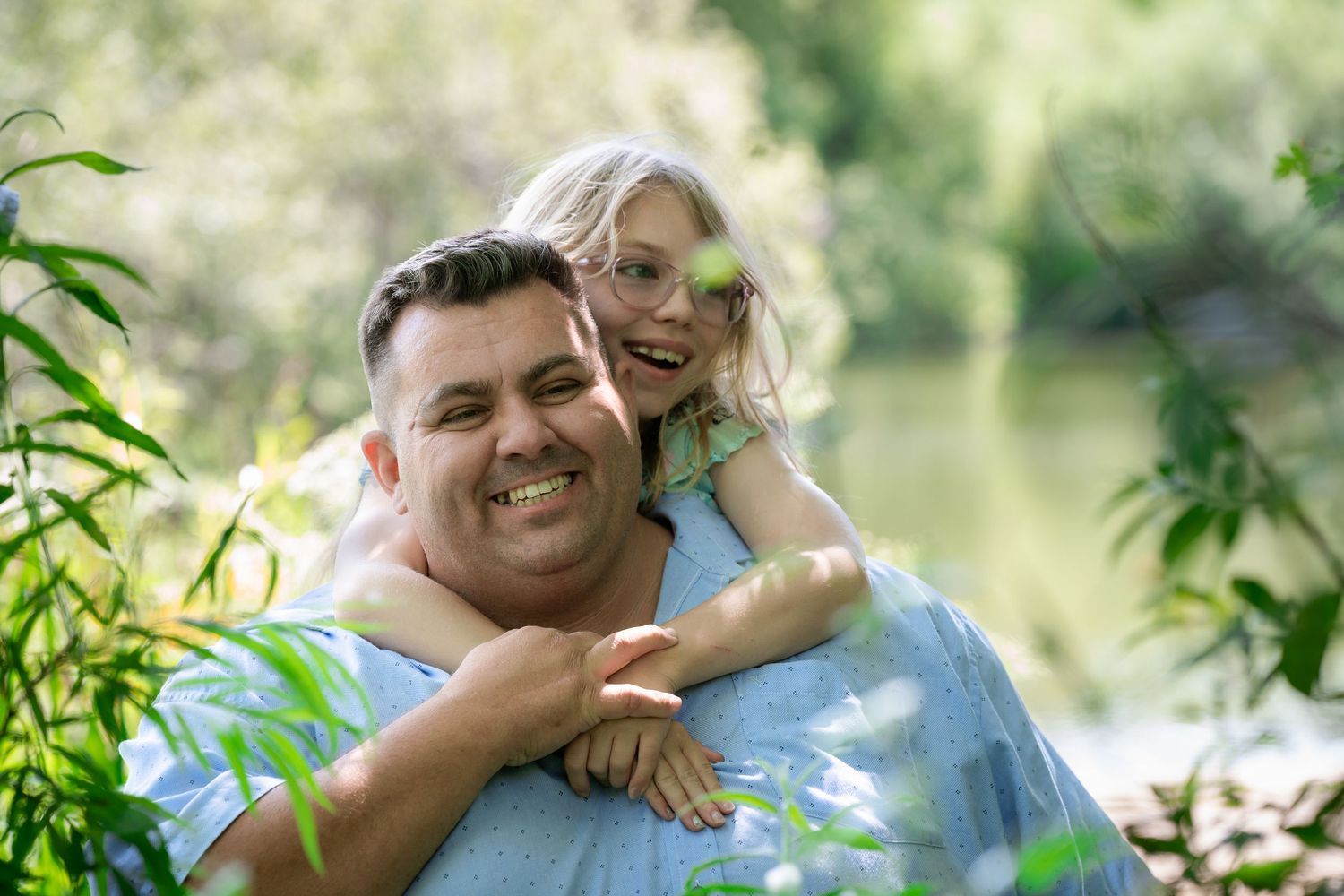 Two people sharing a joyful moment together outdoors near a pond.