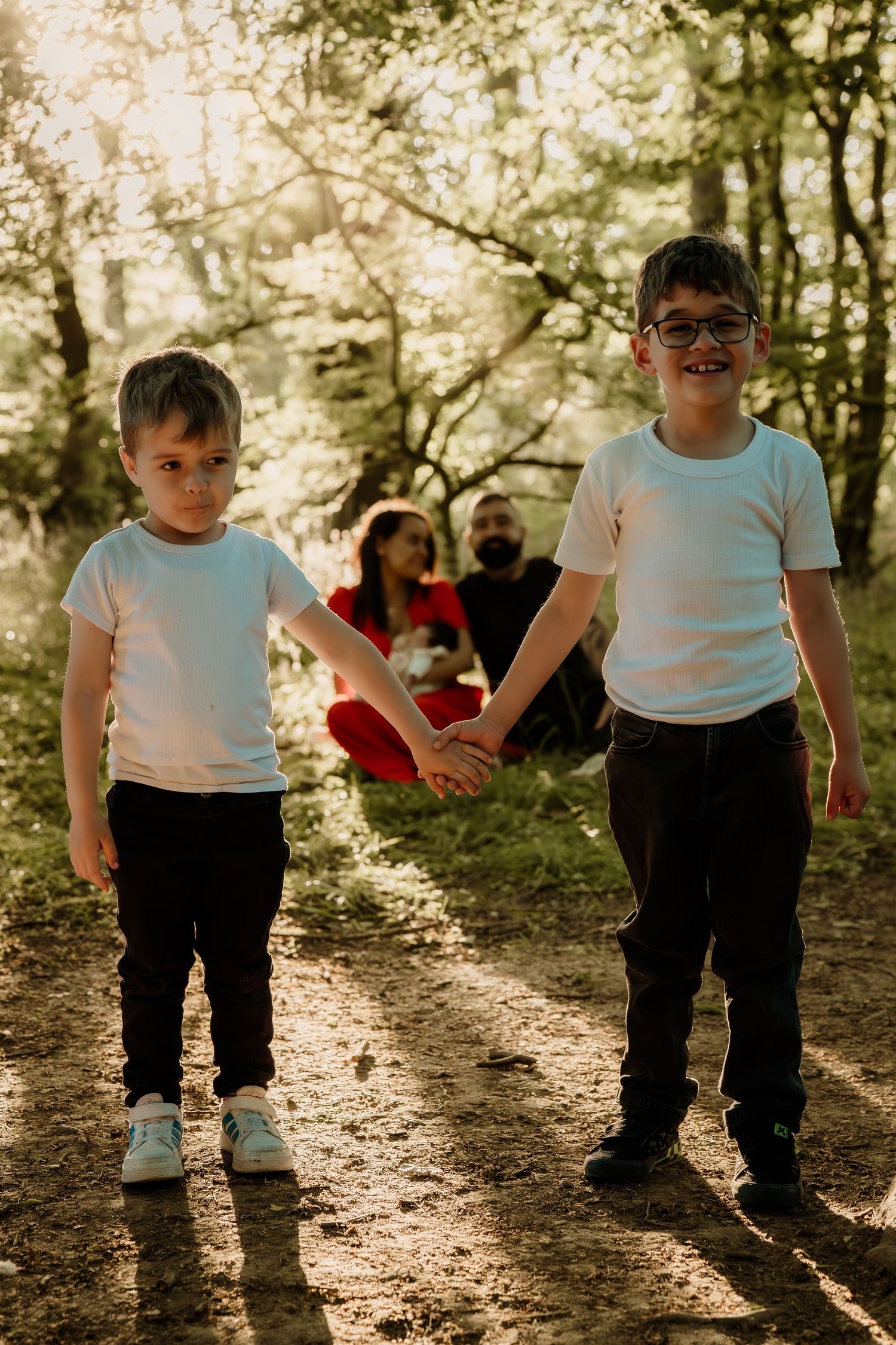 Children walking through a sunlit forest path with golden light filtering through trees.