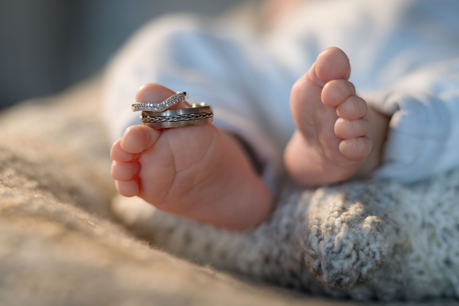 Tiny baby feet wearing an engagement ring in a soft portrait shot.