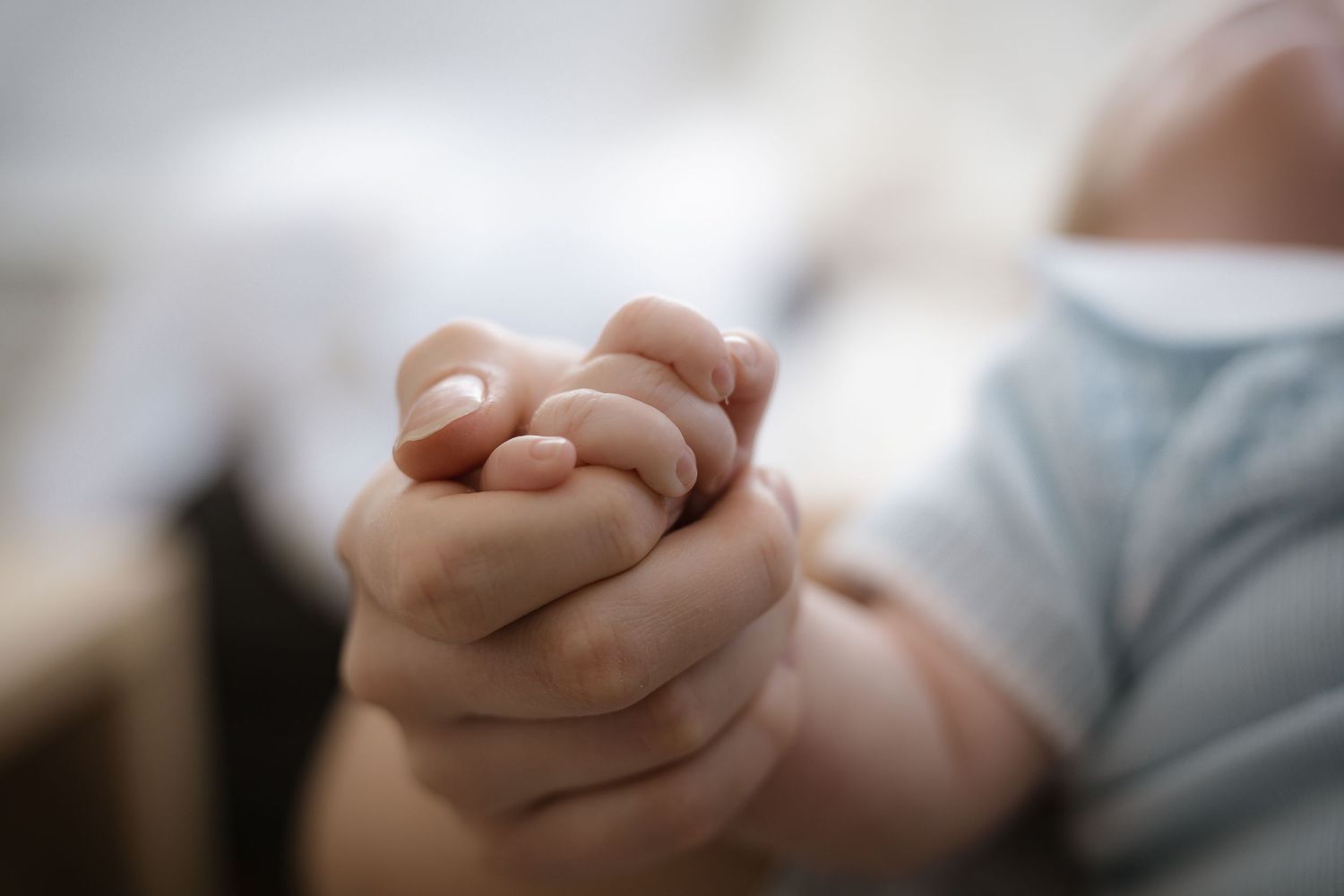 Close-up shot of tiny baby hands clasped together.