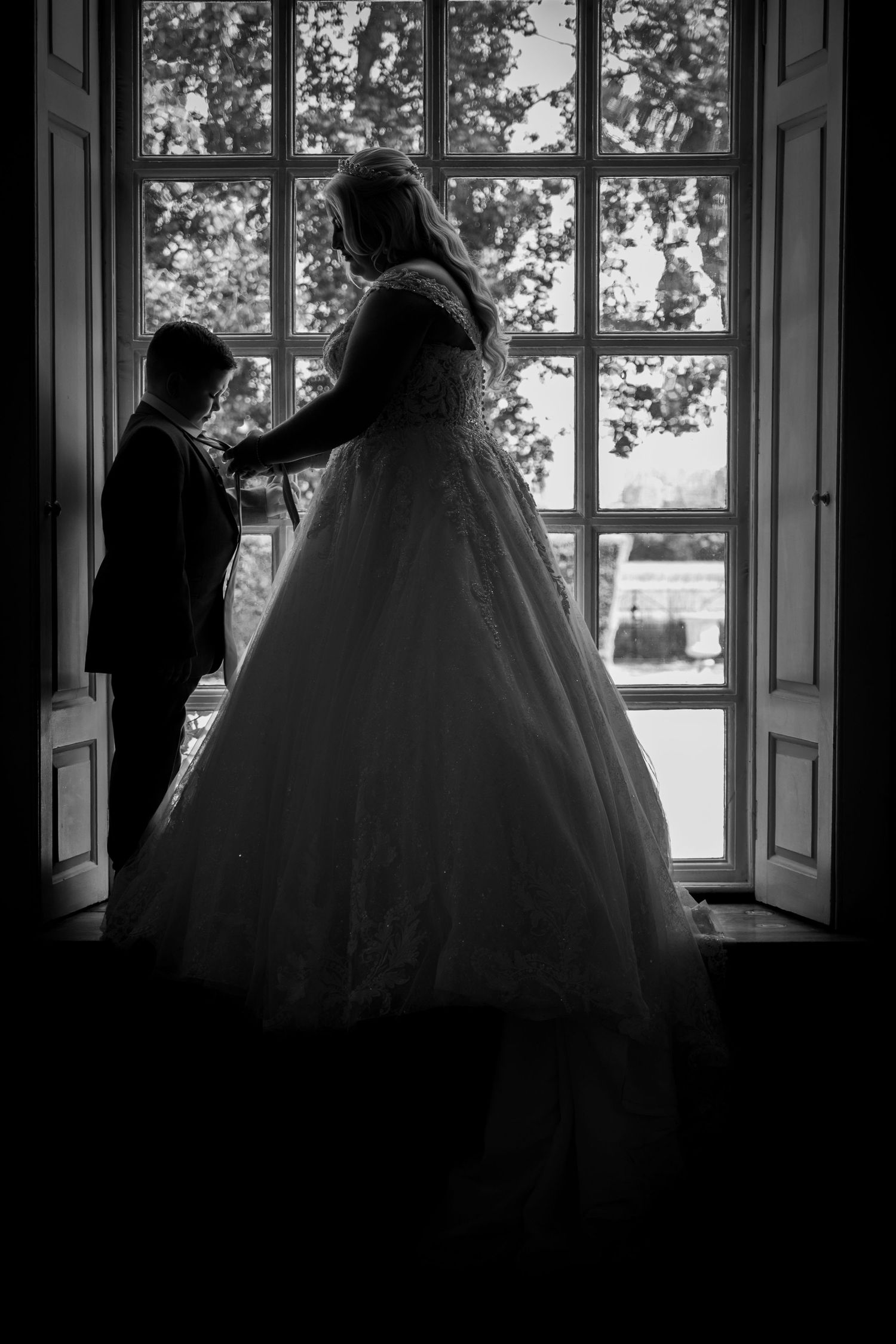 A silhouetted wedding moment captured through a window in black and white.