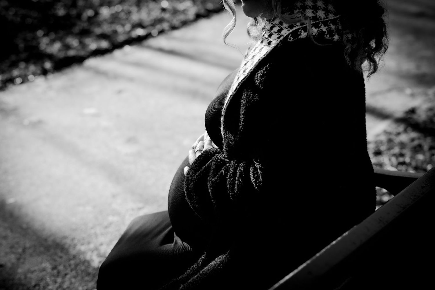 Silhouette of pregnant woman's belly in dark lighting against textured background.