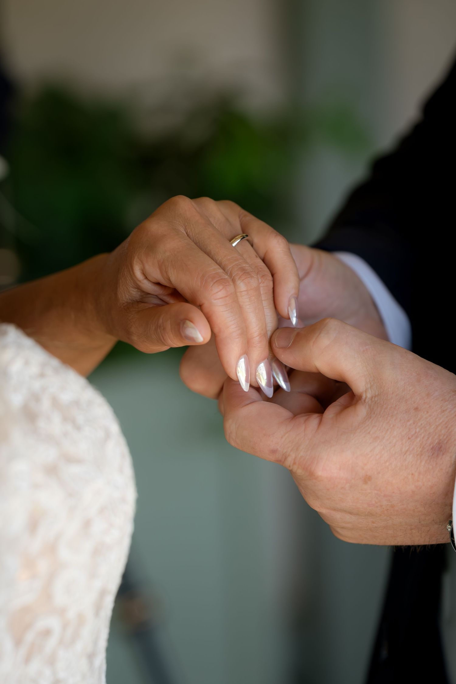 Close-up shot of hands exchanging wedding rings during ceremony.