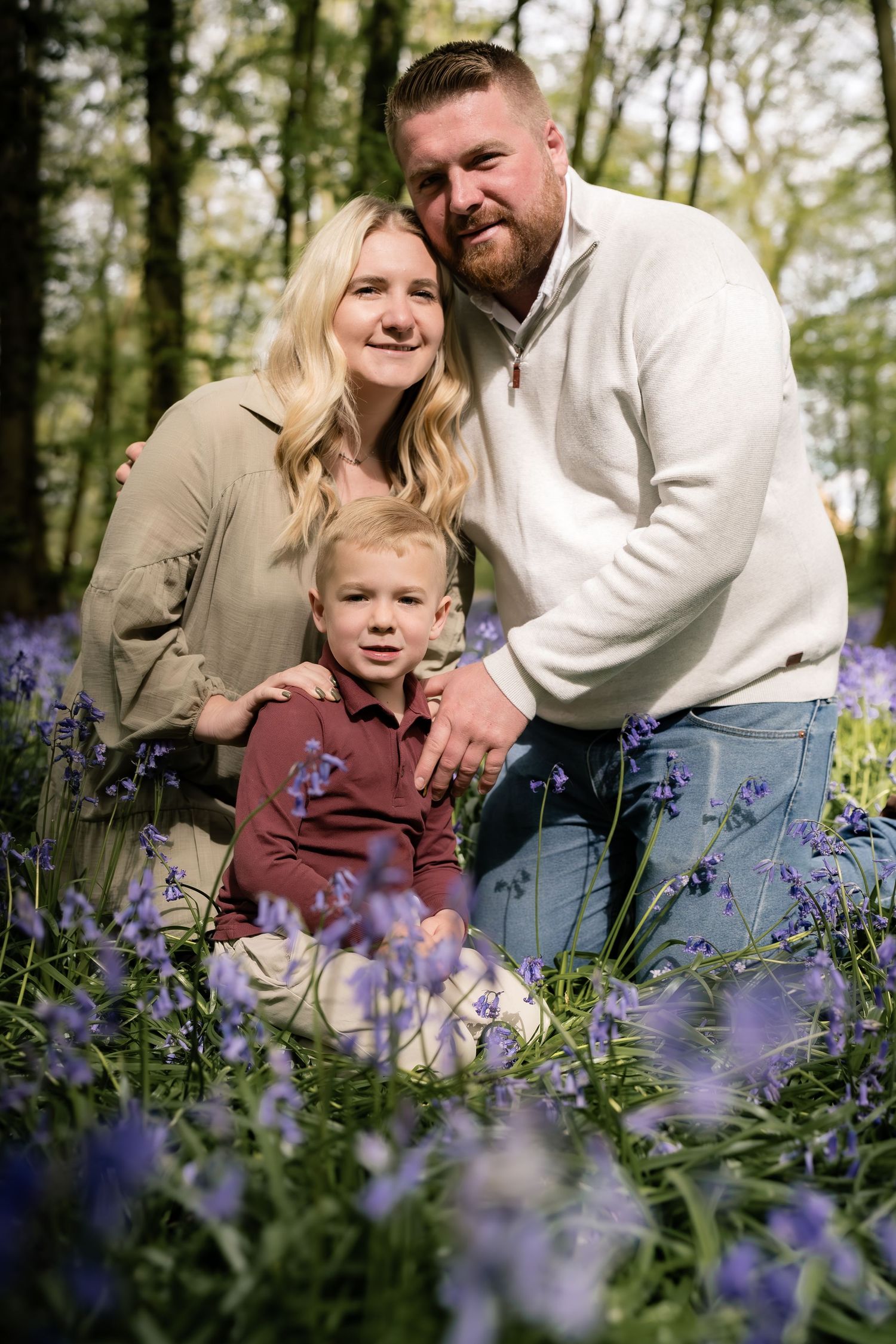 Family portrait amidst a sea of purple bluebells in a spring forest.