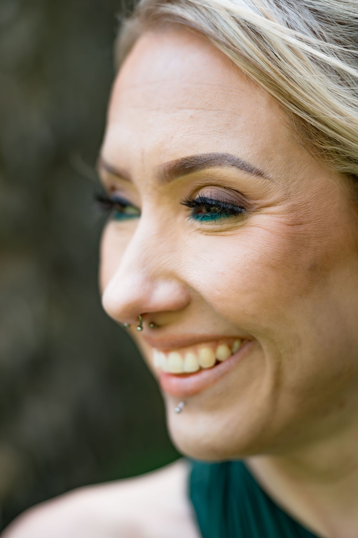 Close-up profile shot showing bright turquoise eye makeup and natural blonde hair against dark background.