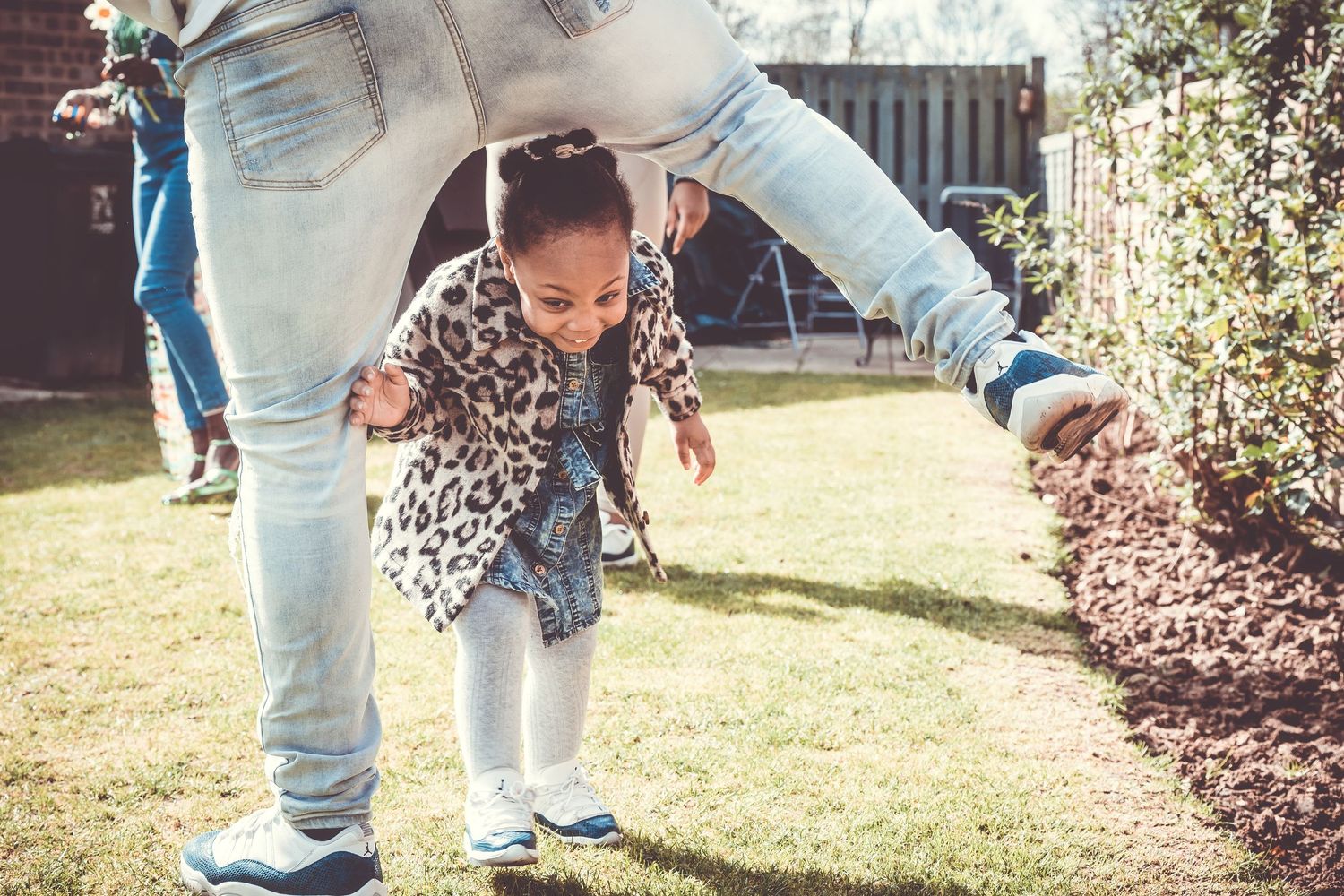 Playful outdoor scene with people in denim and leopard print clothing in a garden.