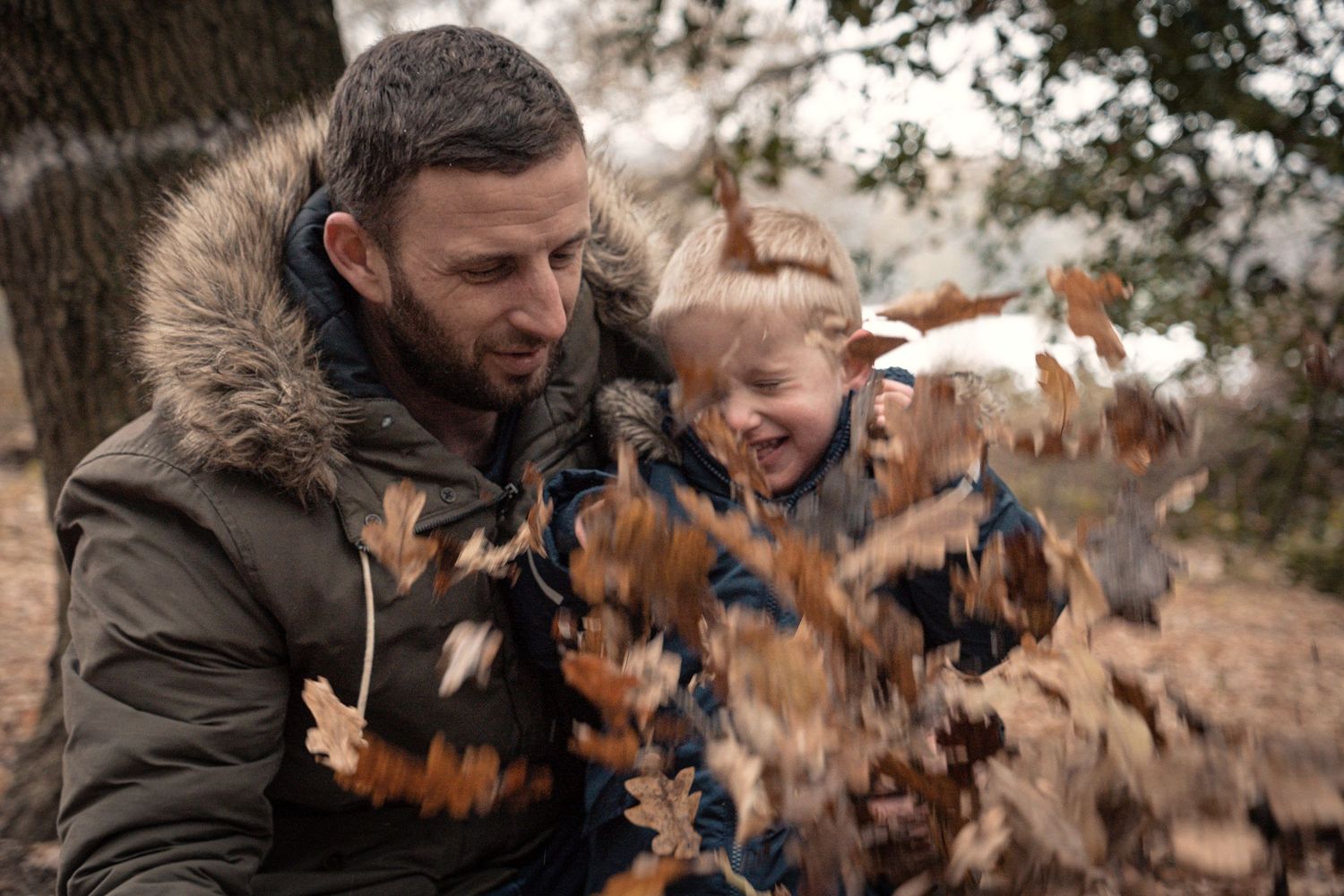 People playing and throwing autumn leaves in the air during a fall photoshoot.