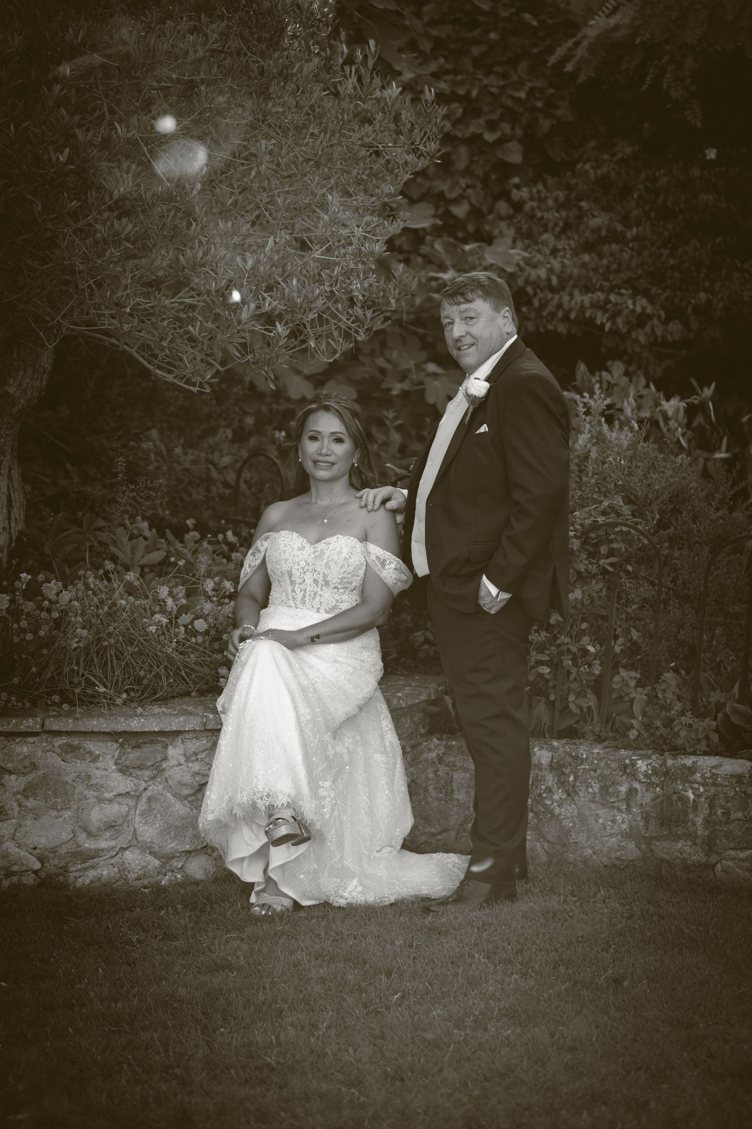 A vintage-style wedding portrait in black and white against a garden backdrop.