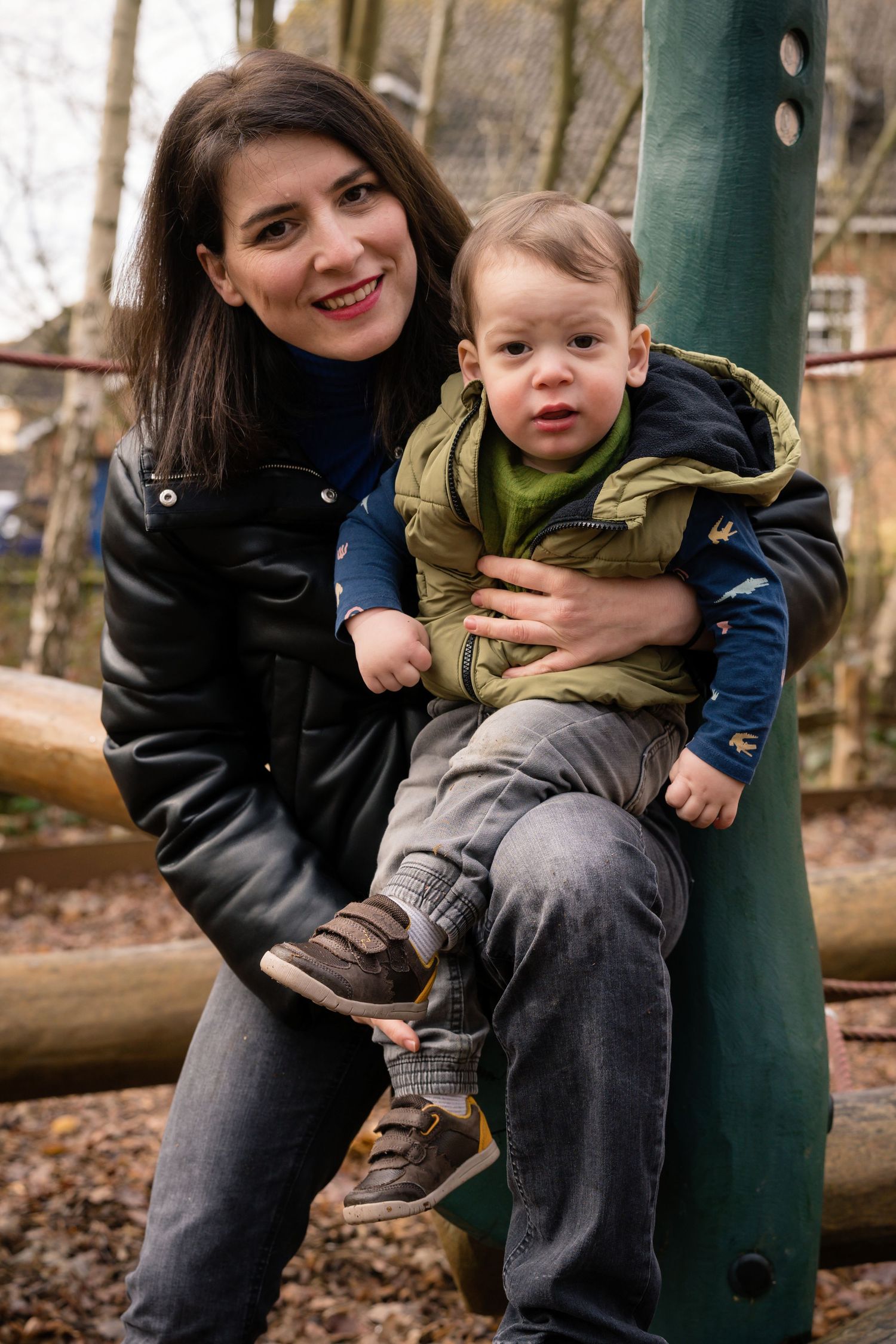 Playful outdoor portraits taken against rustic woodland backdrop.