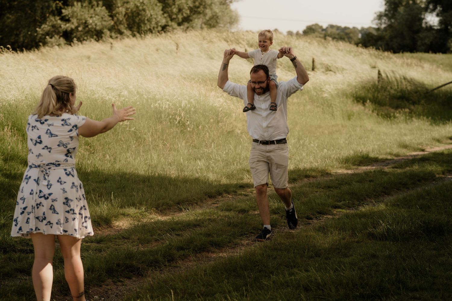 Family playing and having fun on path through summer meadow.