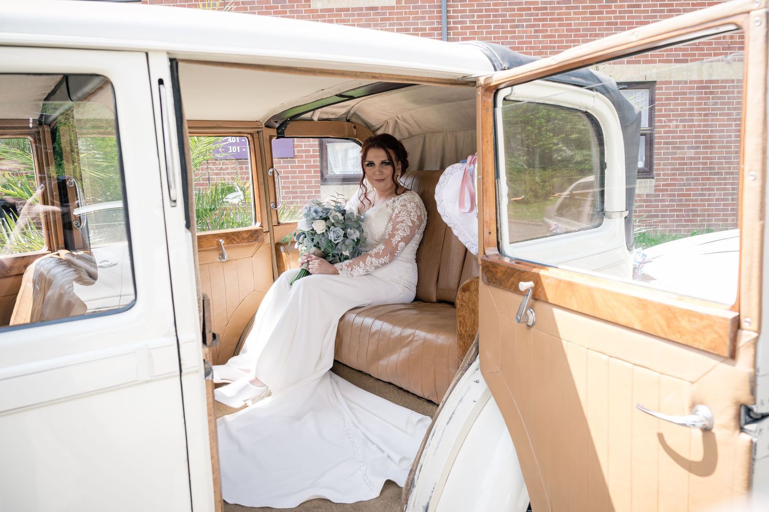 A classic cream-colored vintage wedding car with elegant leather interior awaits its passengers.