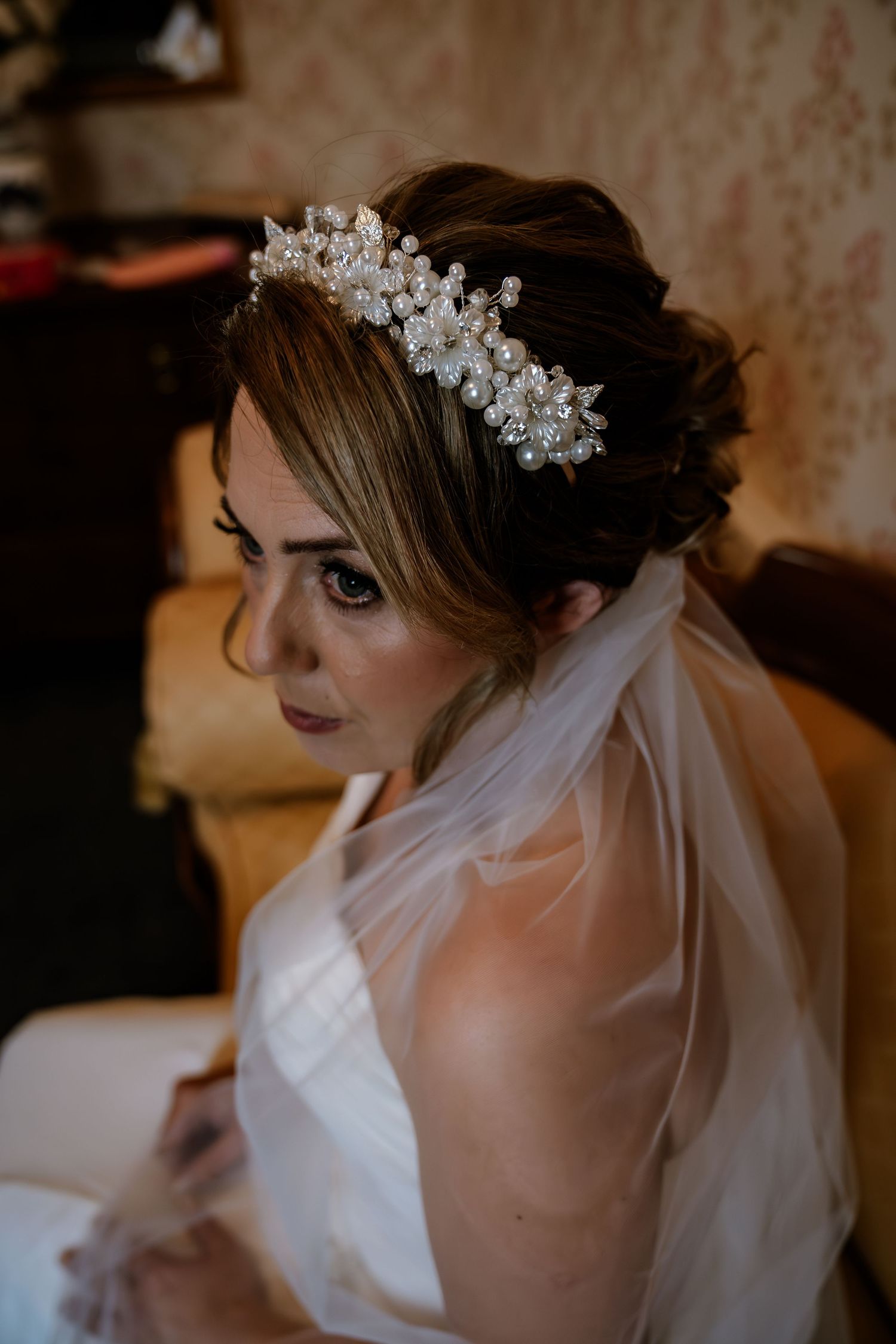 A detailed shot of a crystal bridal tiara and veil against an elegant updo.