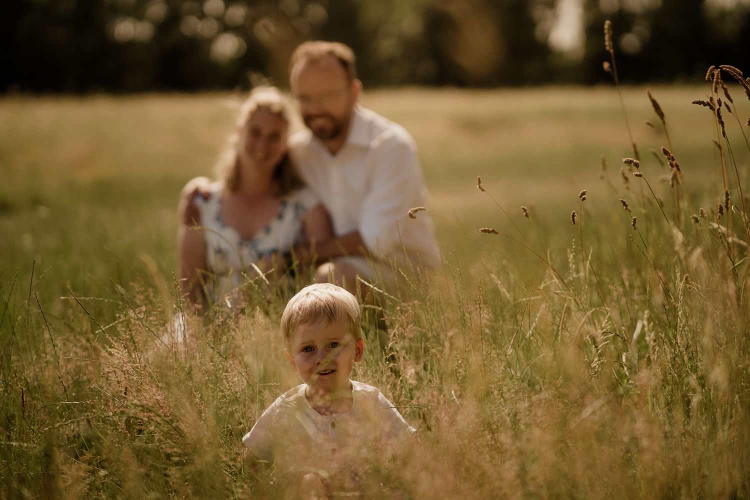 Family outdoors in golden meadow during sunset photo session.