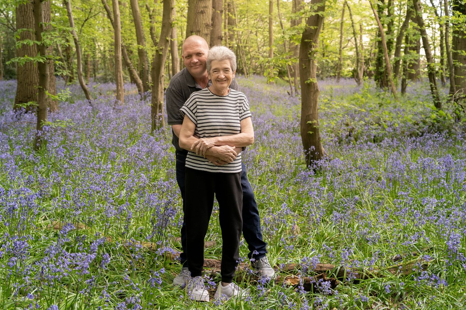 Couple standing together in beautiful bluebell forest.