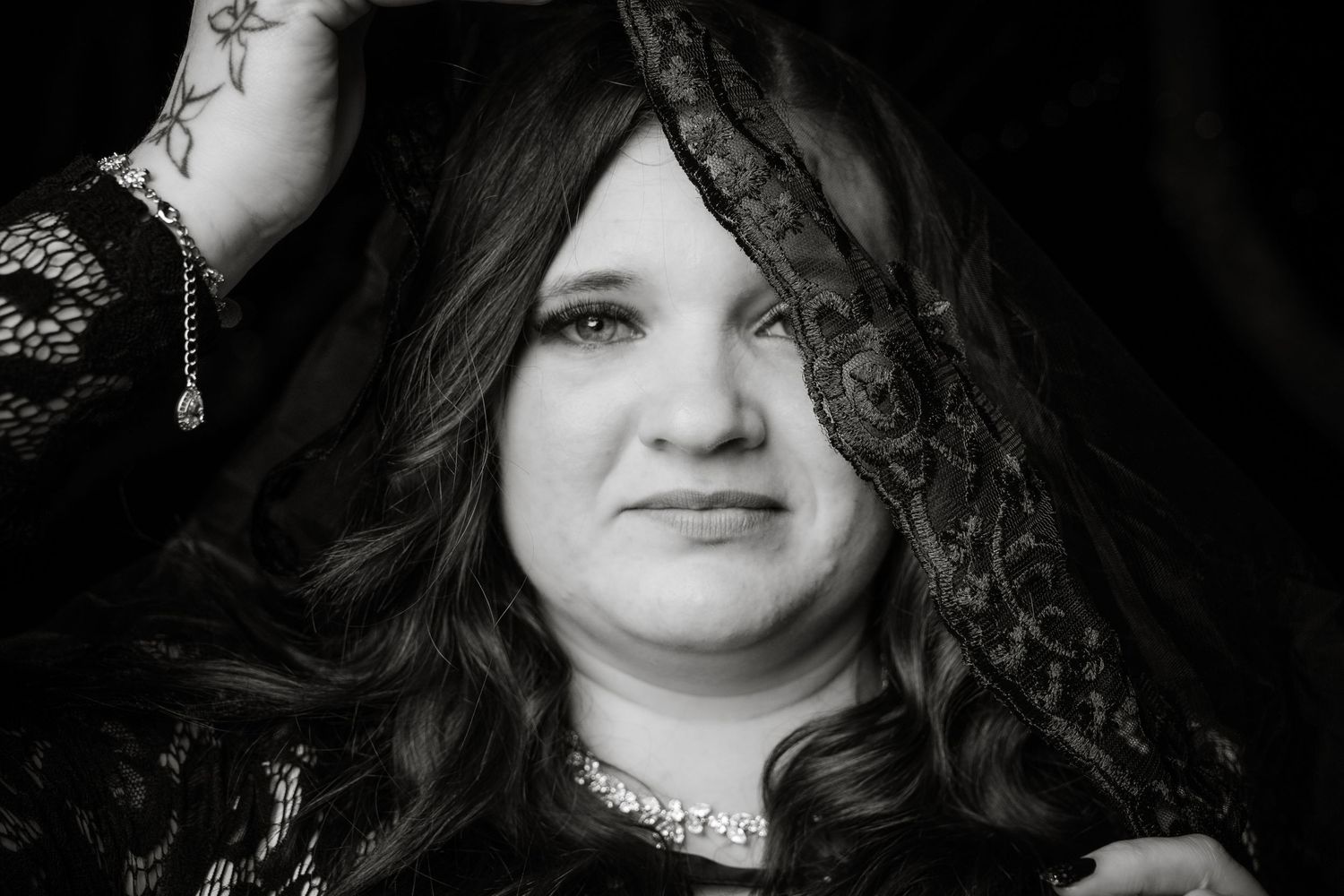 An artistic black and white portrait with lace veil detailing.