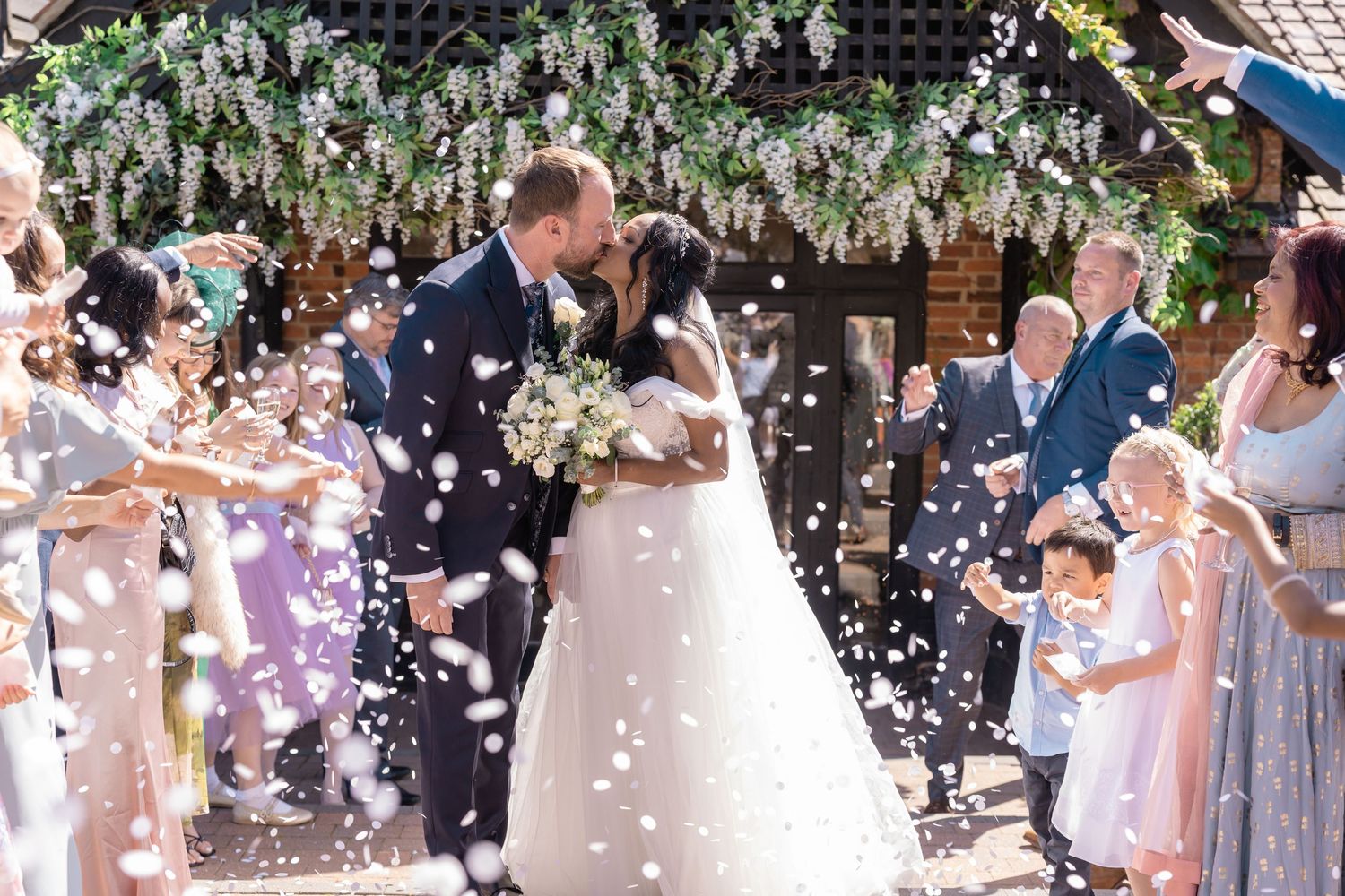 Wedding guests shower the newlyweds with confetti as they exit the ceremony.