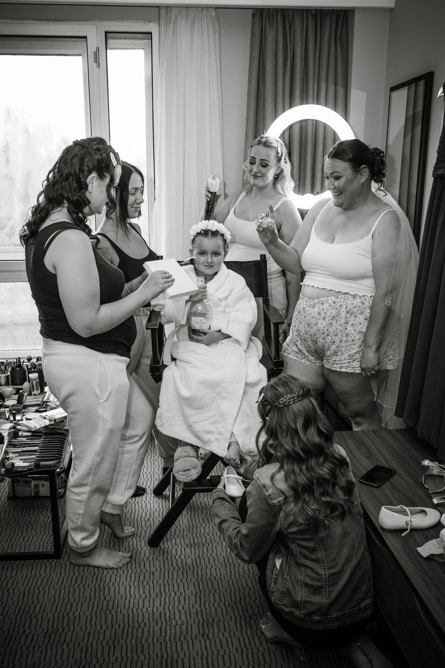 Black and white photo of wedding party getting ready in hotel room.