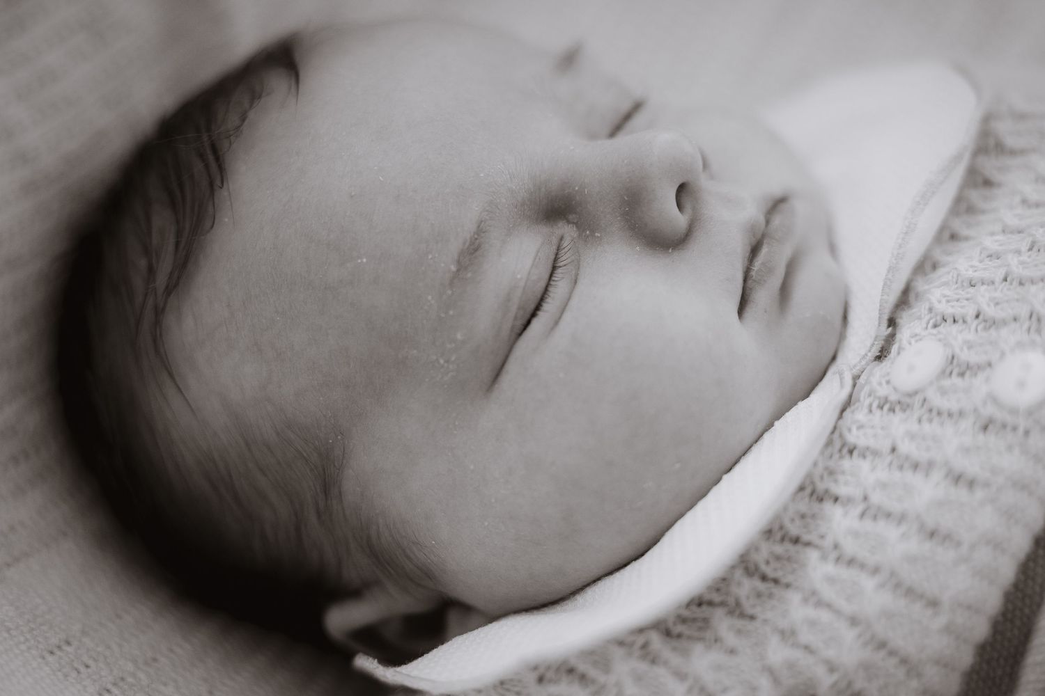 Peaceful sleeping newborn in black and white with soft lighting.