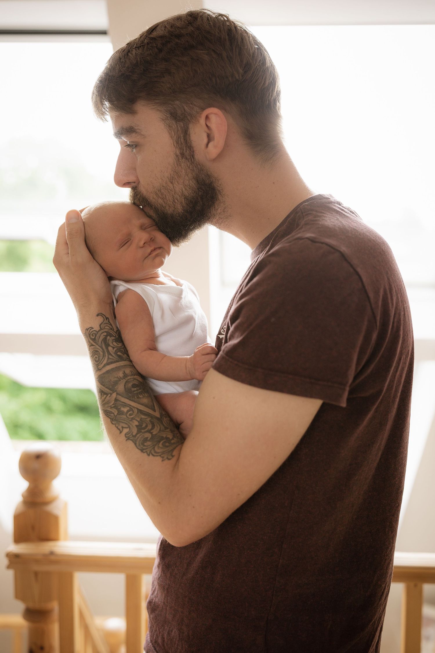 A tender moment between a baby and caregiver near a sunlit window.