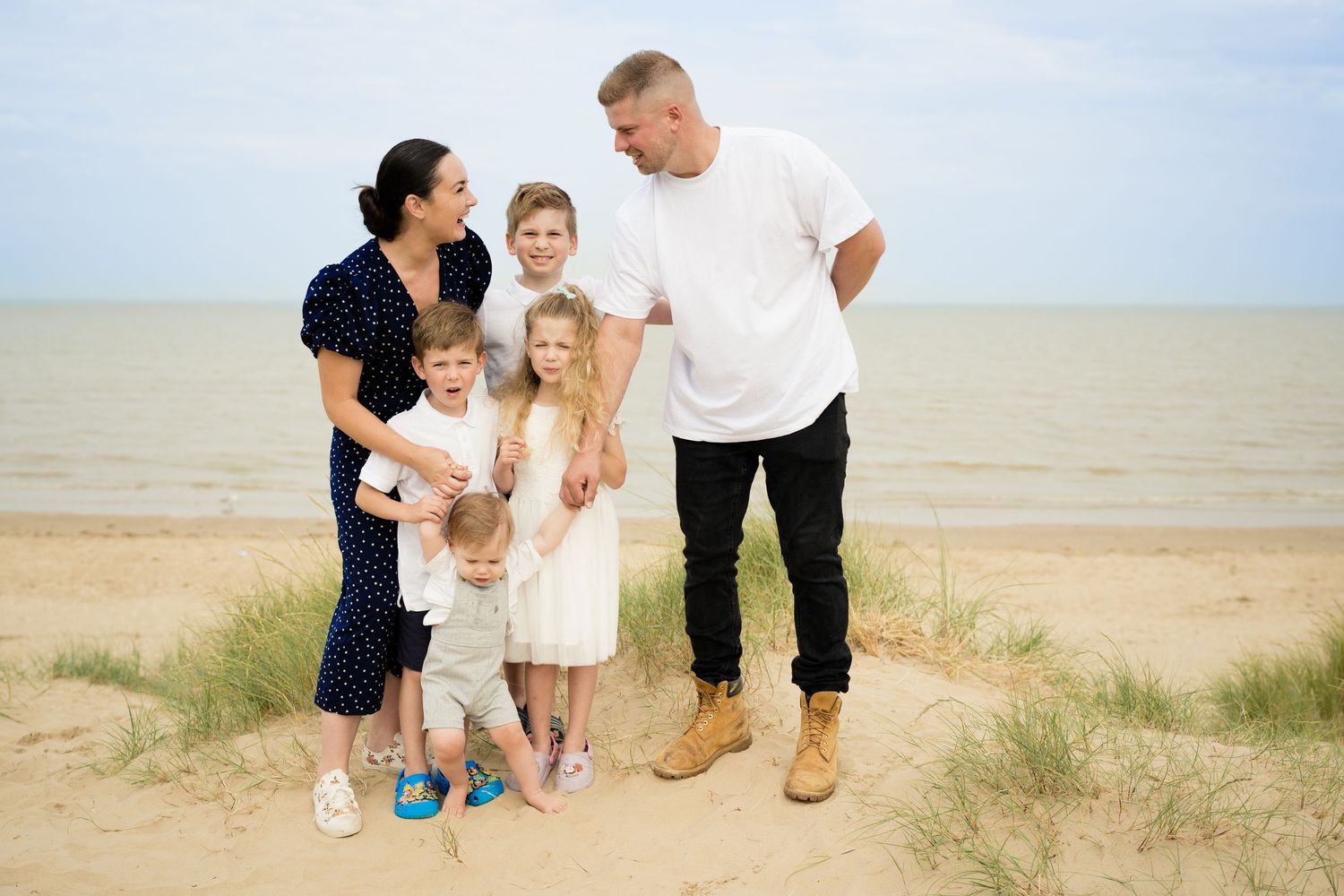 Family playing together on a sandy beach during a bright summer day.