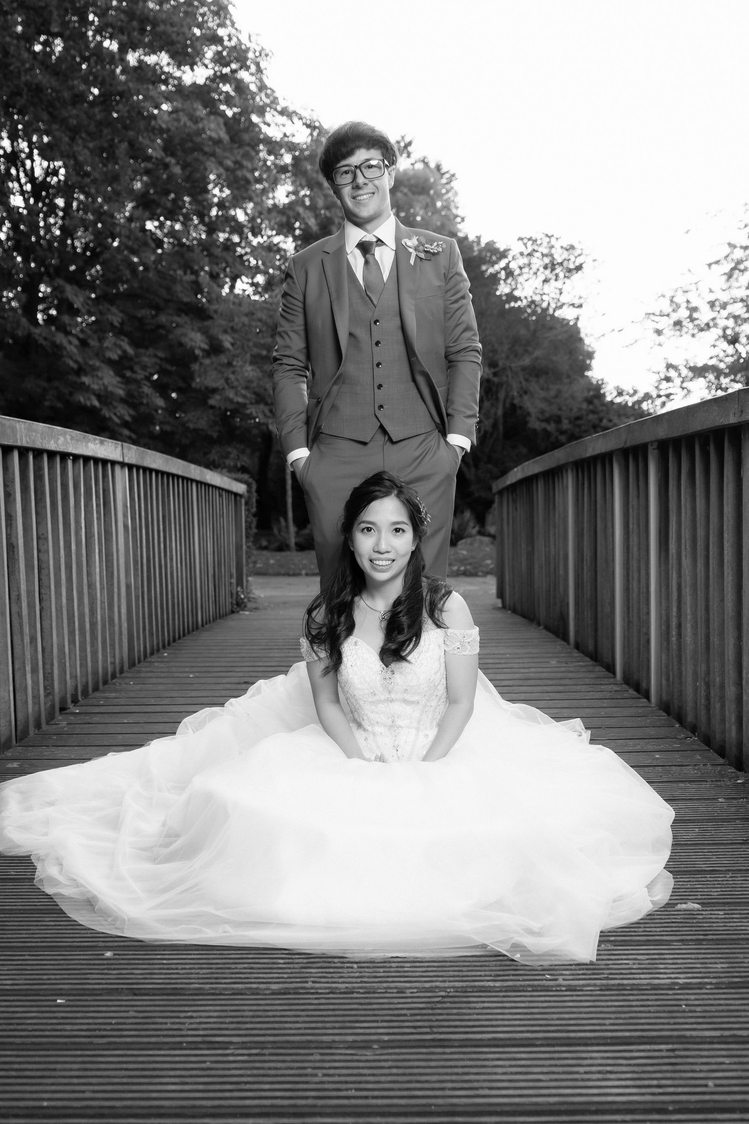 A creative black and white wedding photo taken on a wooden bridge.