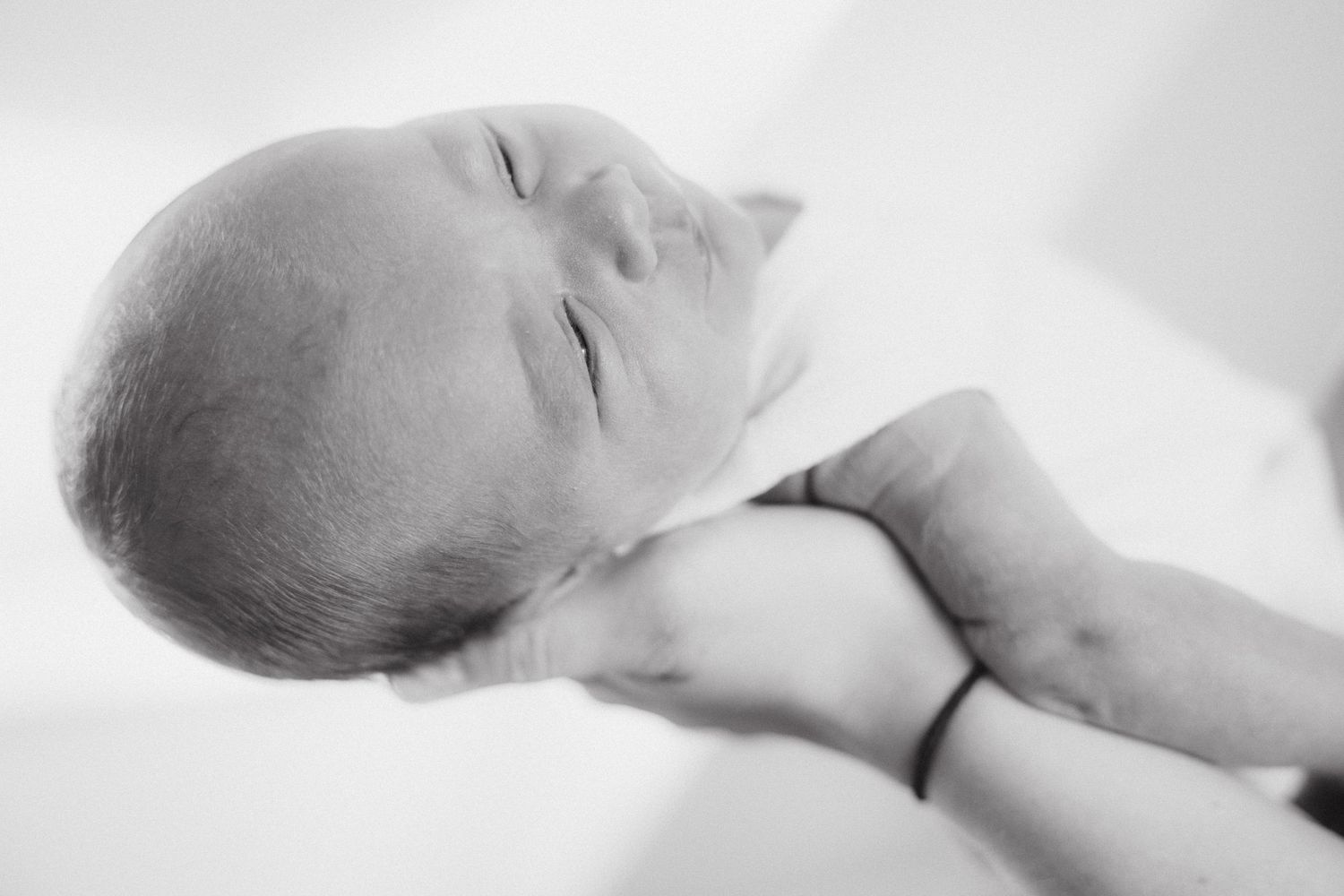 High-key black and white portrait of a sleeping newborn baby.