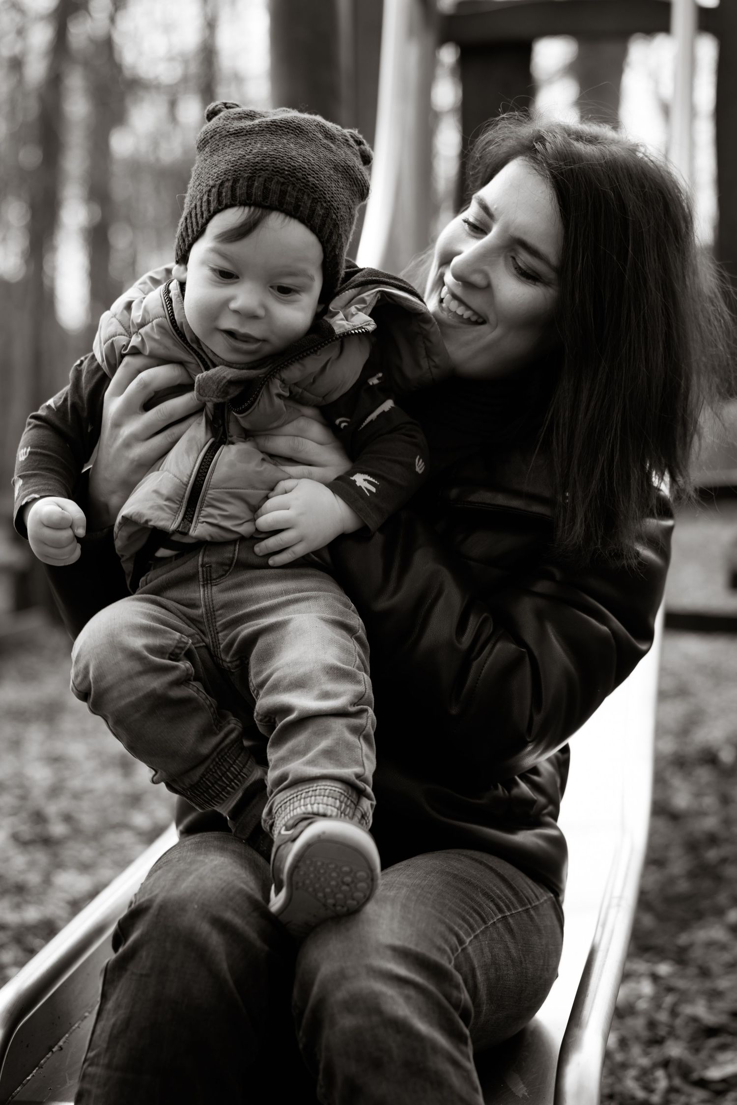 Black and white portrait of a winter outdoor playtime moment on a playground slide.