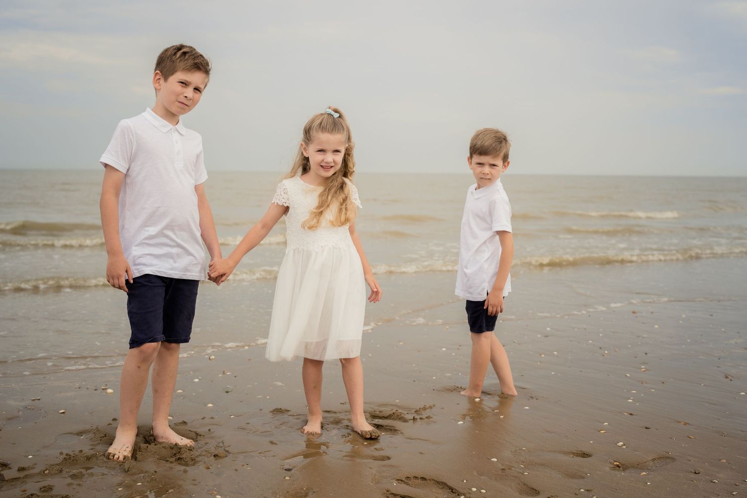Family members walking barefoot along shoreline during beach outing.