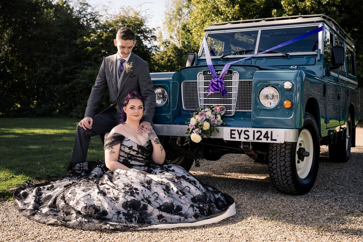 Classic vintage cars parked on gravel at a wedding venue.