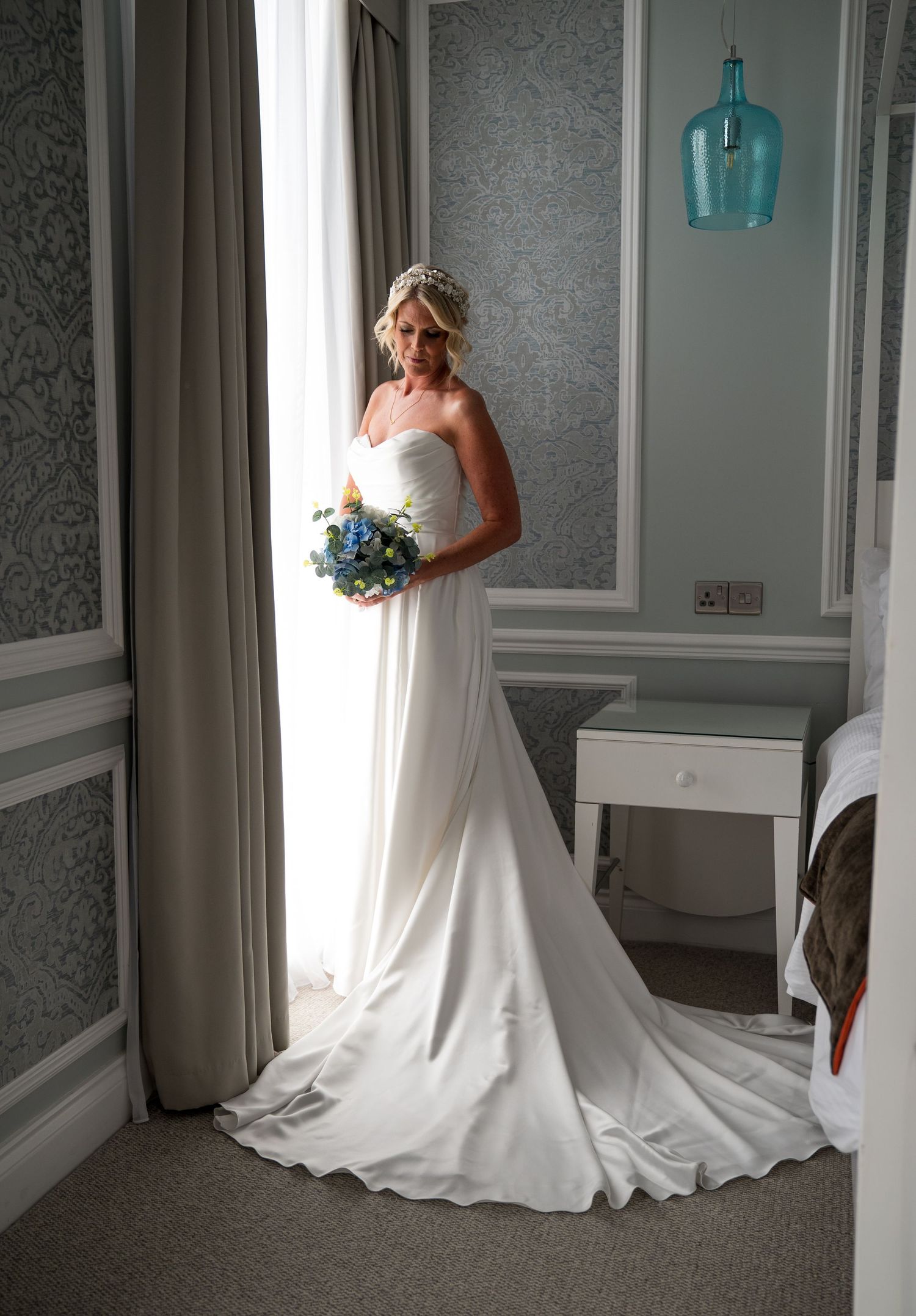 Beautiful wedding dress with flowing train photographed in an elegant room with blue accents.