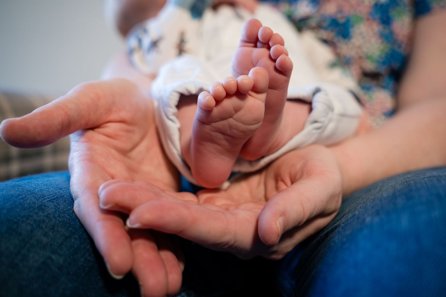 Close-up of tiny newborn baby feet cradled in adult hands.