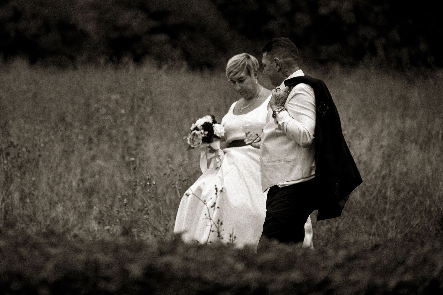 Romantic black and white portrait of couple embracing in a meadow during their wedding day.