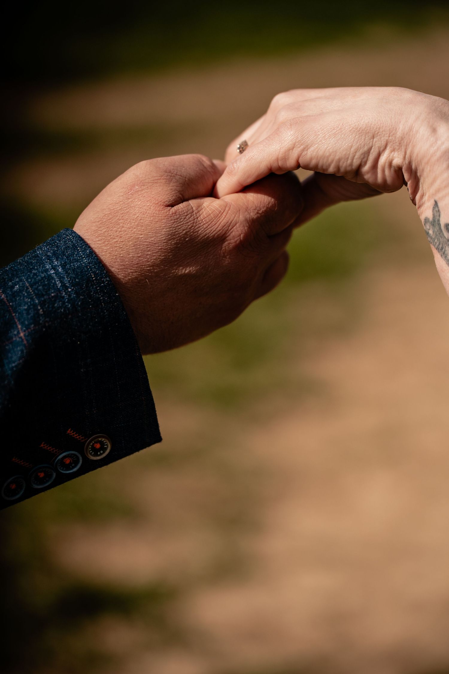 Two hands reaching out to touch each other tenderly against a blurred outdoor background in warm sunlight.