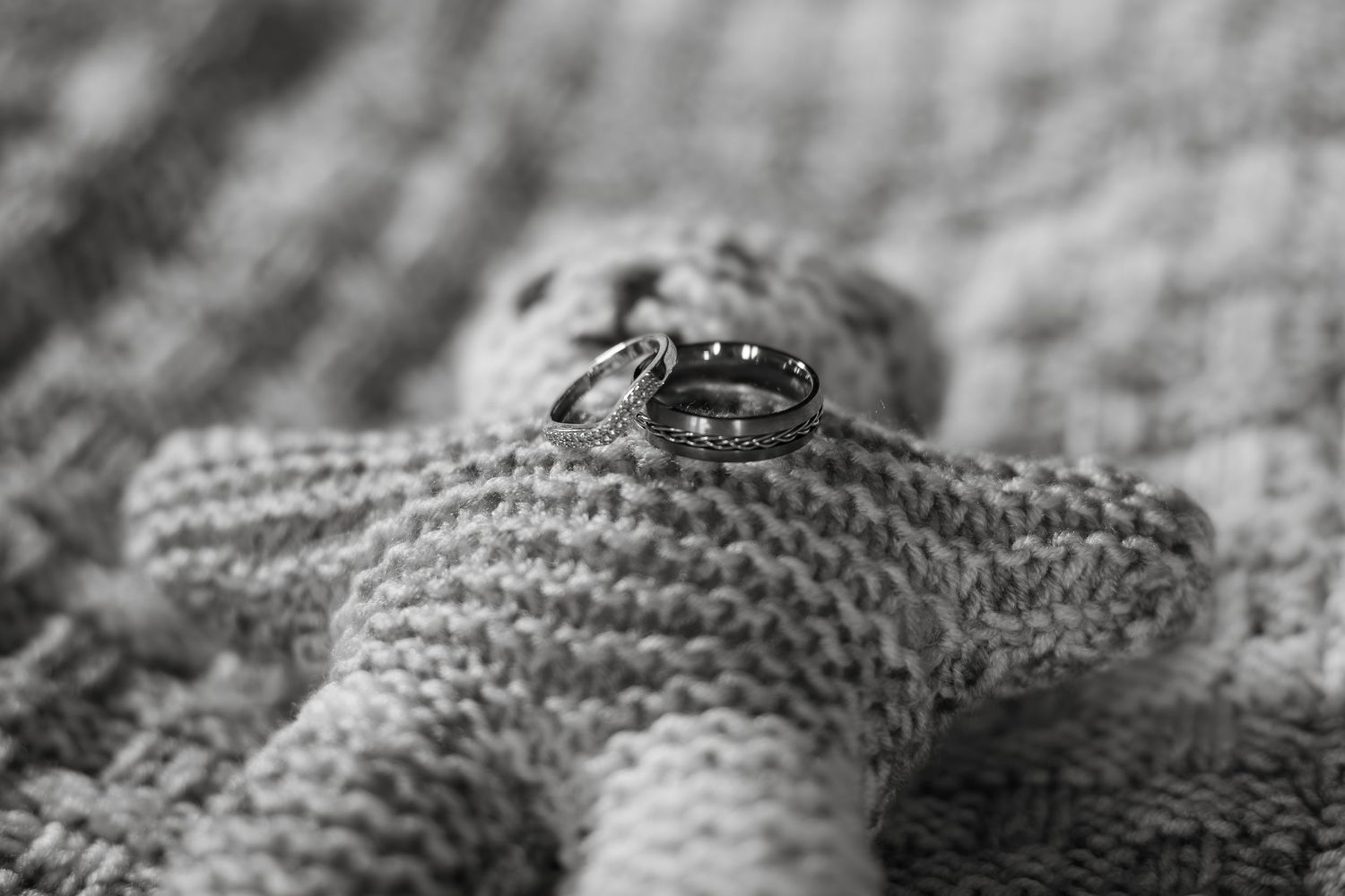 Wedding rings displayed on a knitted star-shaped surface in black and white.