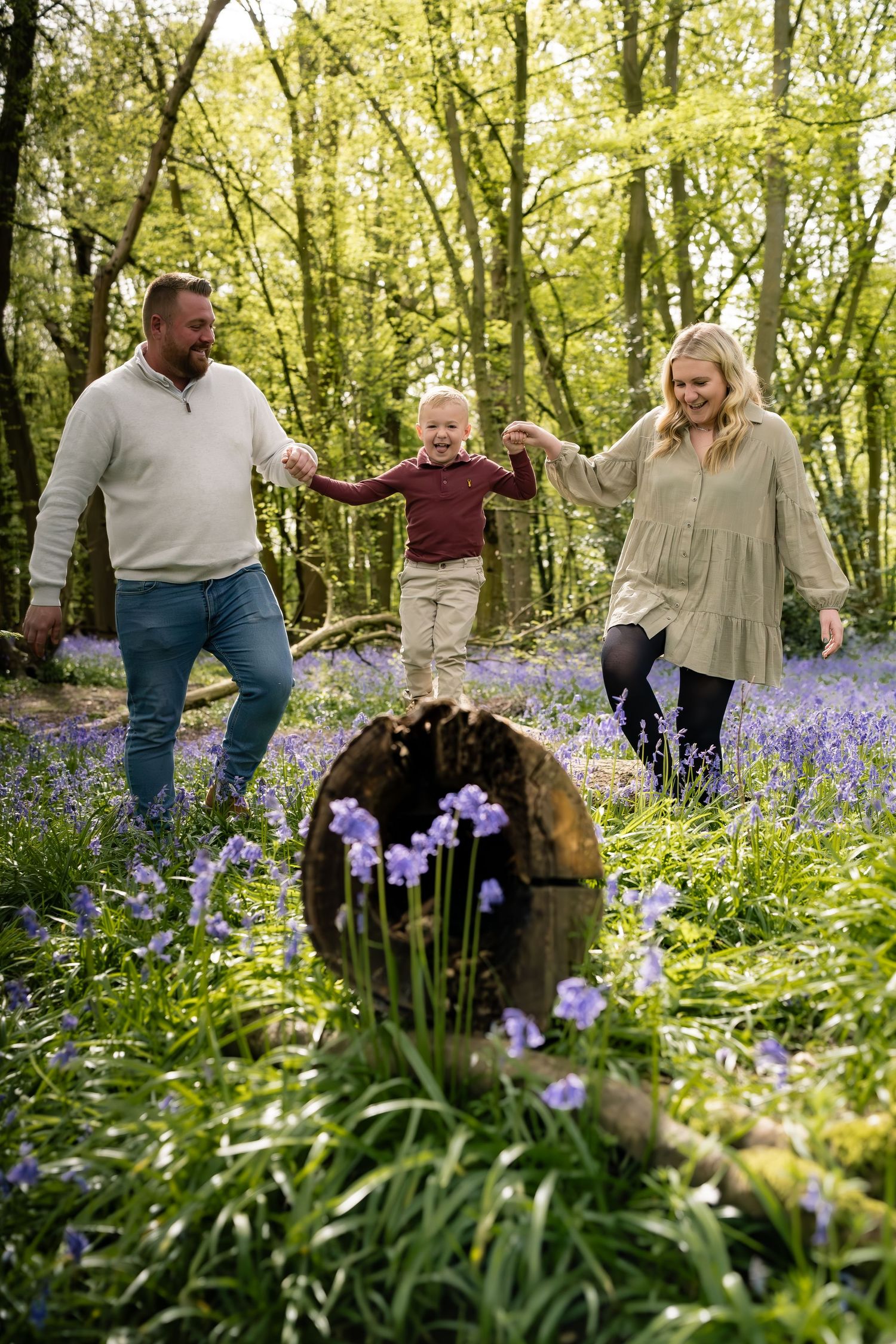 A joyful family moment in a forest filled with blooming bluebells as they hold hands and play together.