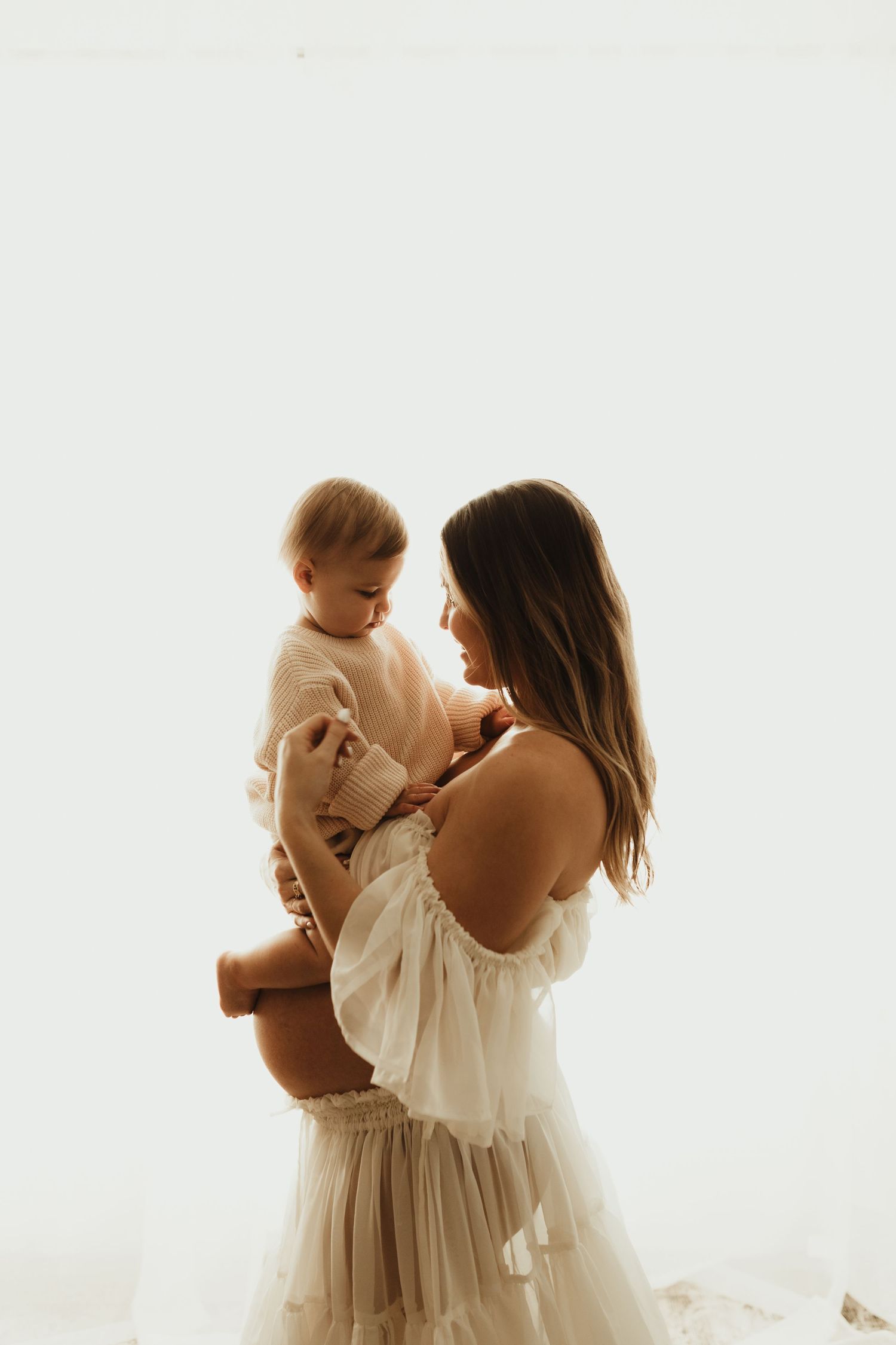 A series of ethereal photos showing tender moments between parent and child in soft white drapery against a light backdrop.
