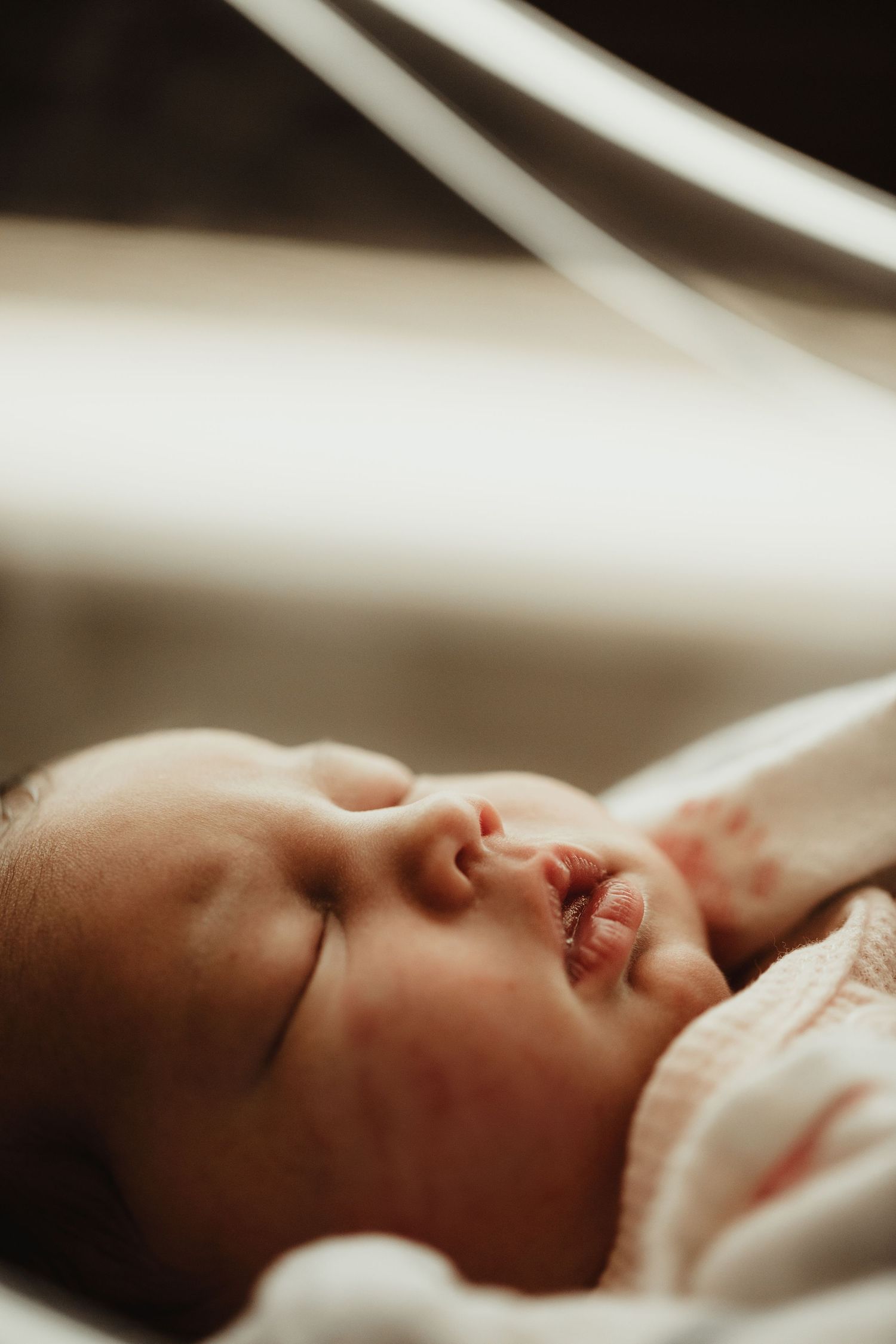 A sleeping newborn baby wrapped in white blankets is viewed in profile from multiple angles.