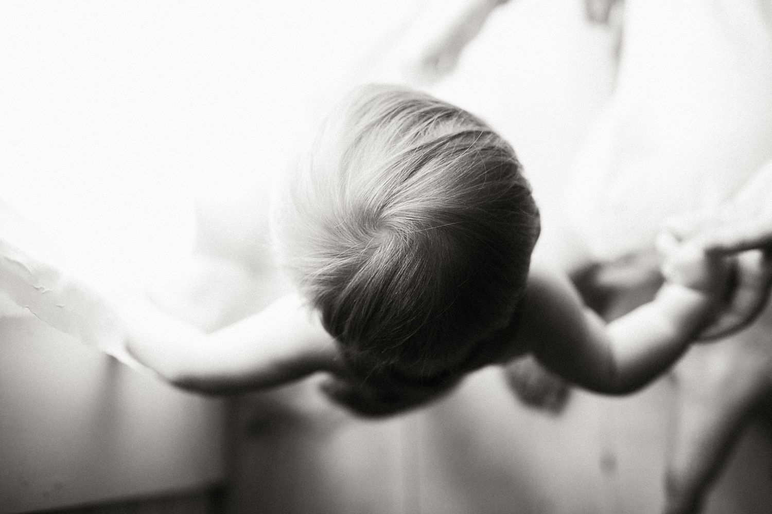 Black and white artistic photograph of a person stretching their arms out in a soft, ethereal lighting.