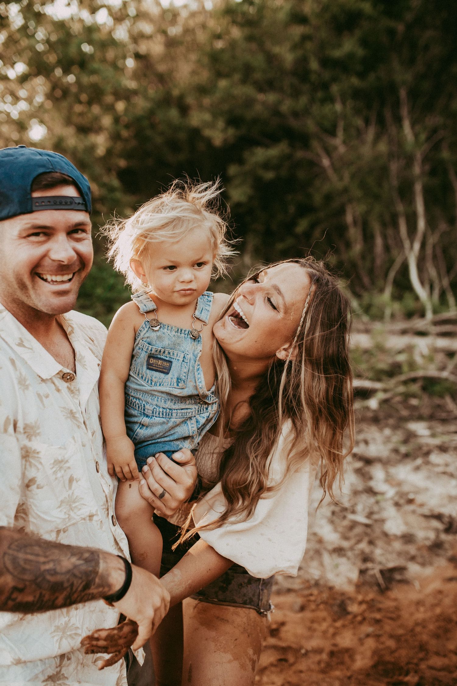 A natural outdoor family photoshoot shows playful and joyful moments on rocky terrain in warm lighting.