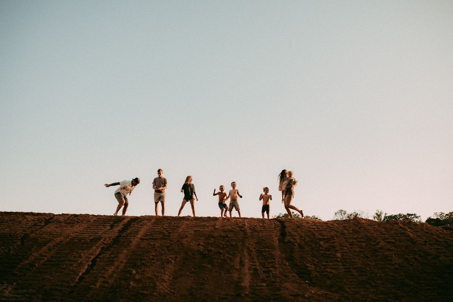 Silhouettes of hikers stand atop a ridge against the golden sunset sky creating a dramatic mountaineering scene.