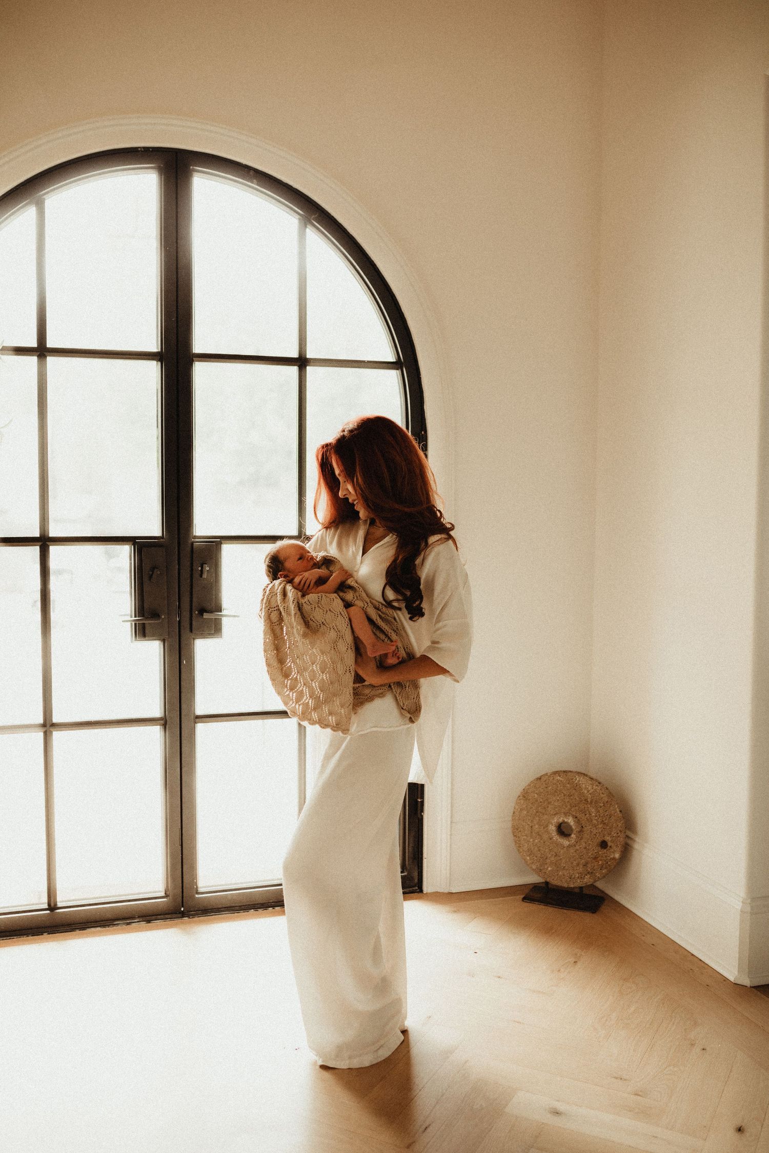 Multiple photos show a figure in a white dress moving gracefully through an empty room with arched windows and wooden floors.