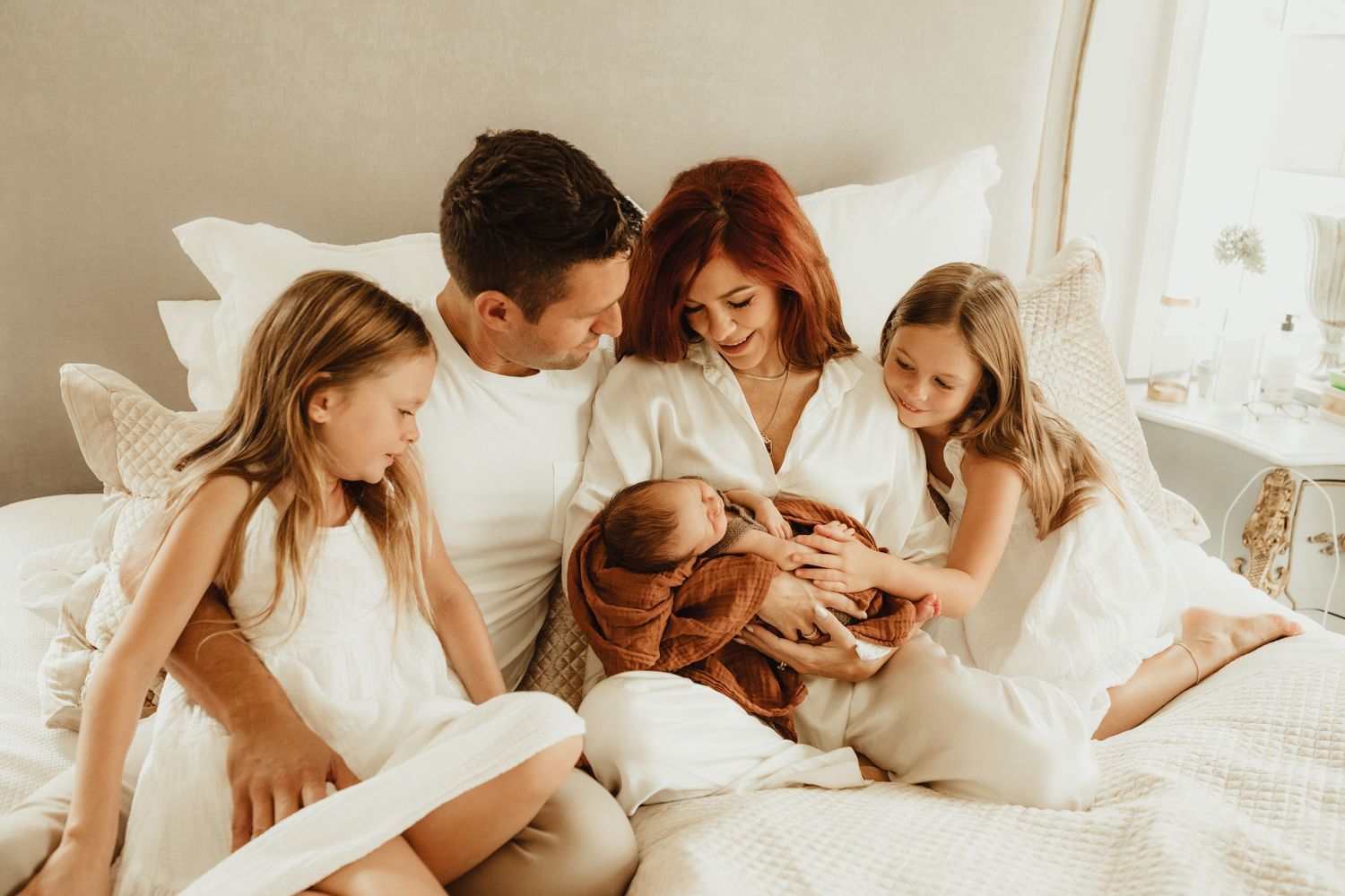 Family gathered together on white bedding sharing an intimate moment.