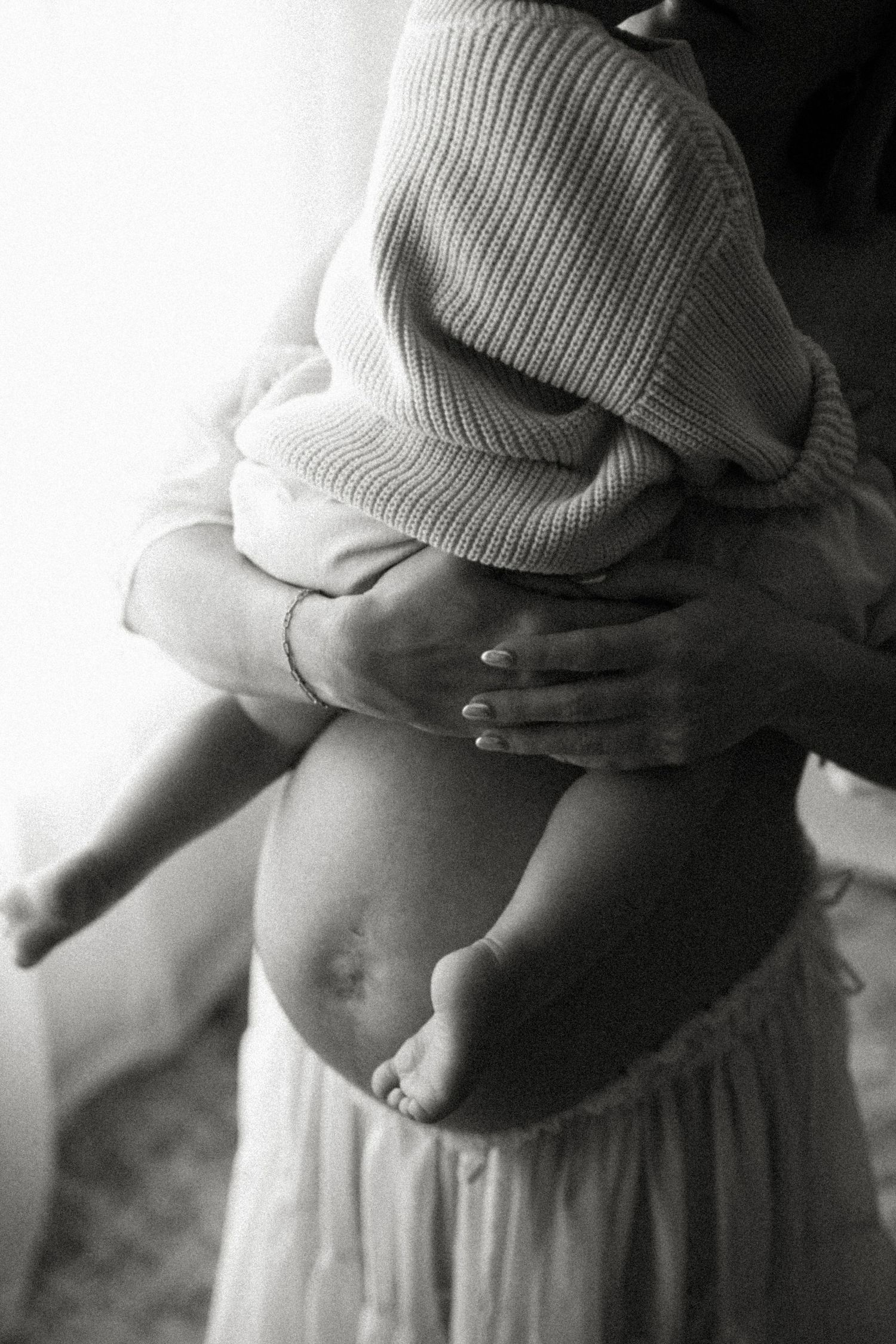 Black and white series of pregnancy photos showing a woman's belly in white clothing against a dark background.