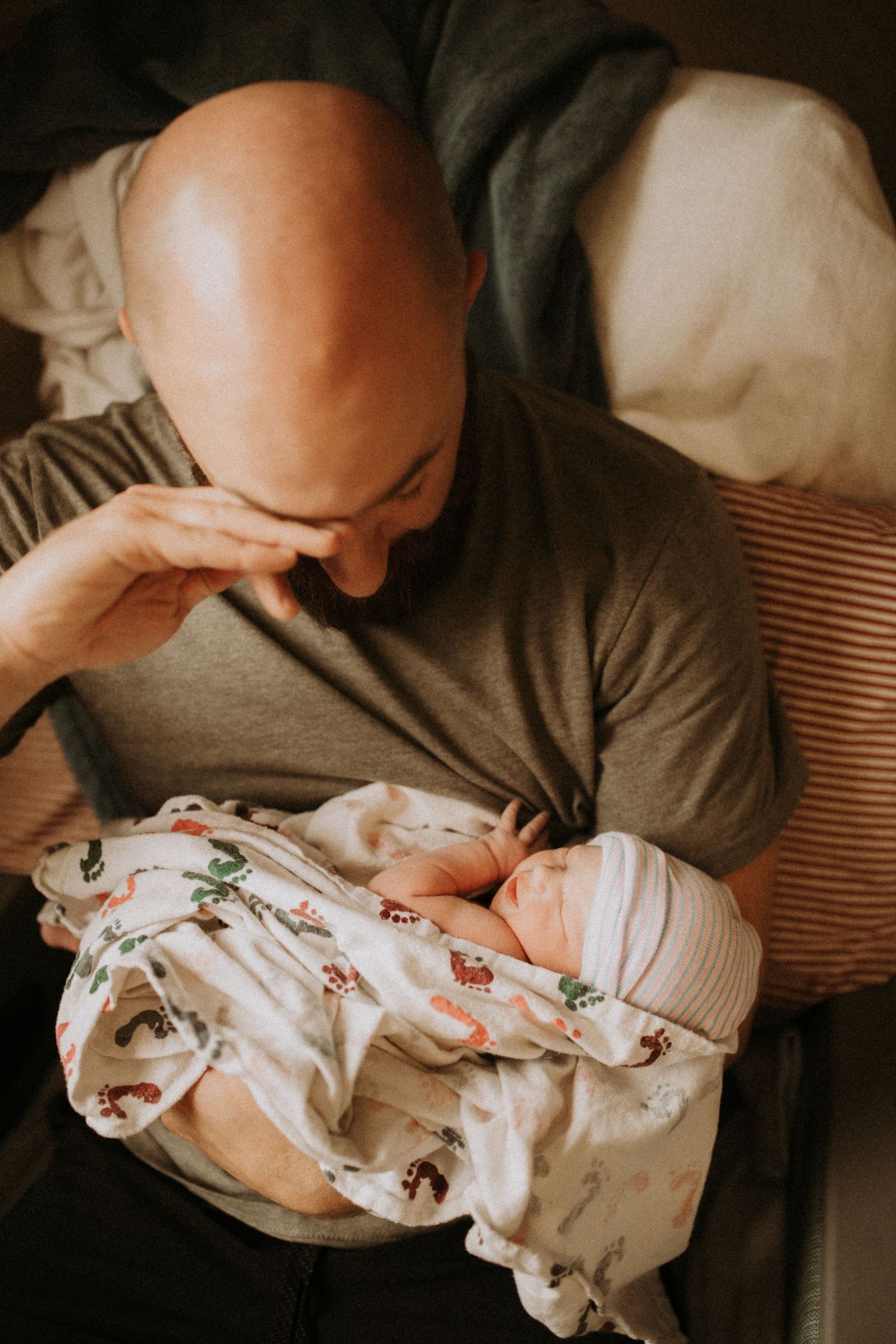 A tender moment showing someone holding a sleeping newborn baby swaddled in floral print fabric.