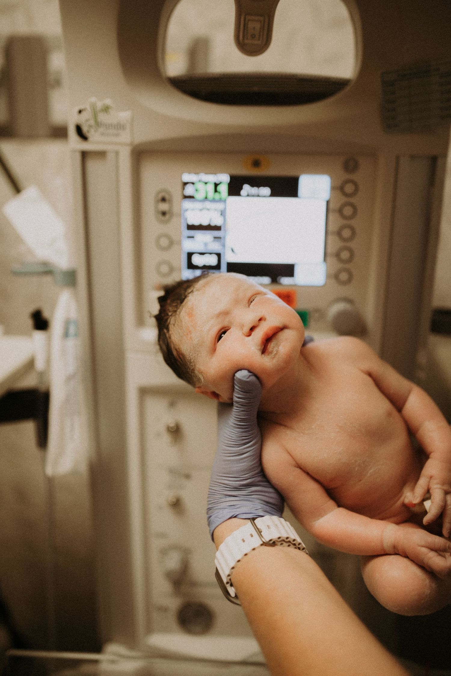 A series of intimate hospital photos showing a newborn baby being cradled during their first moments after birth.
