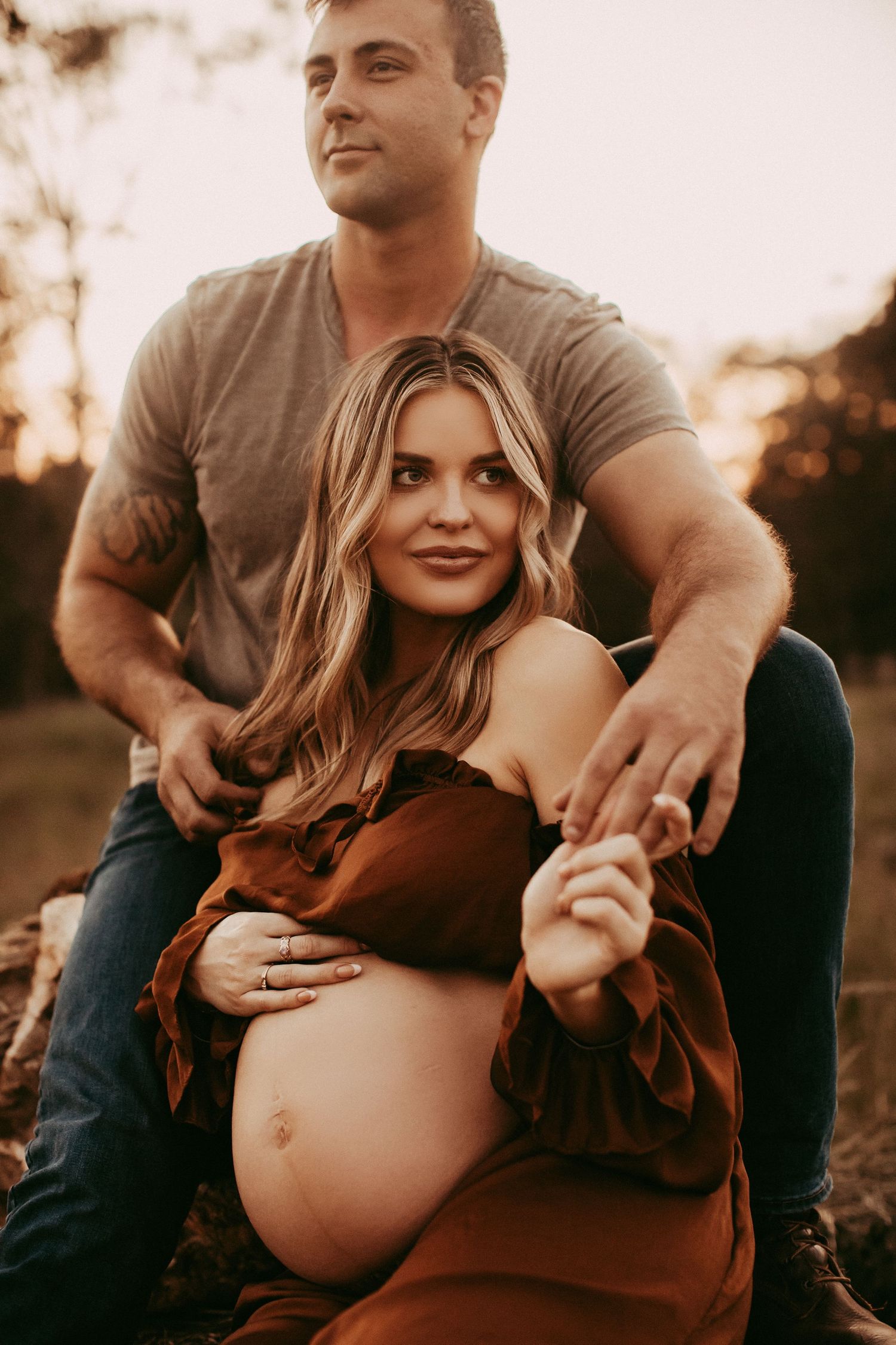 Warm sunset maternity photo series showing couple in casual clothing embracing outdoors in romantic poses.
