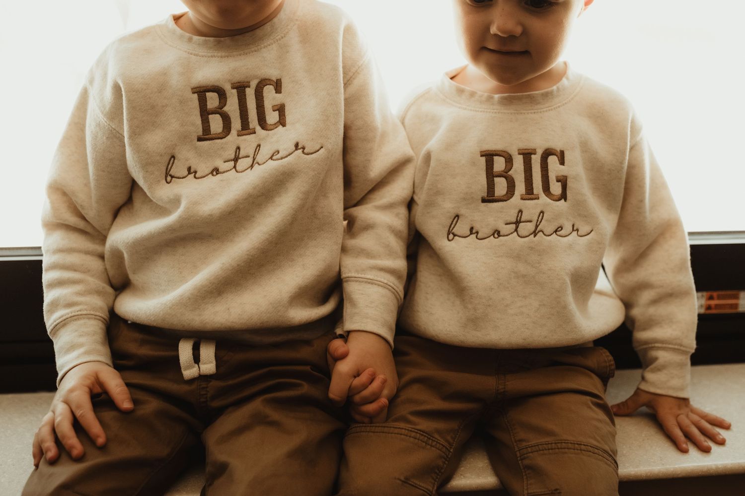Two people wearing matching tan sweatshirts with 
