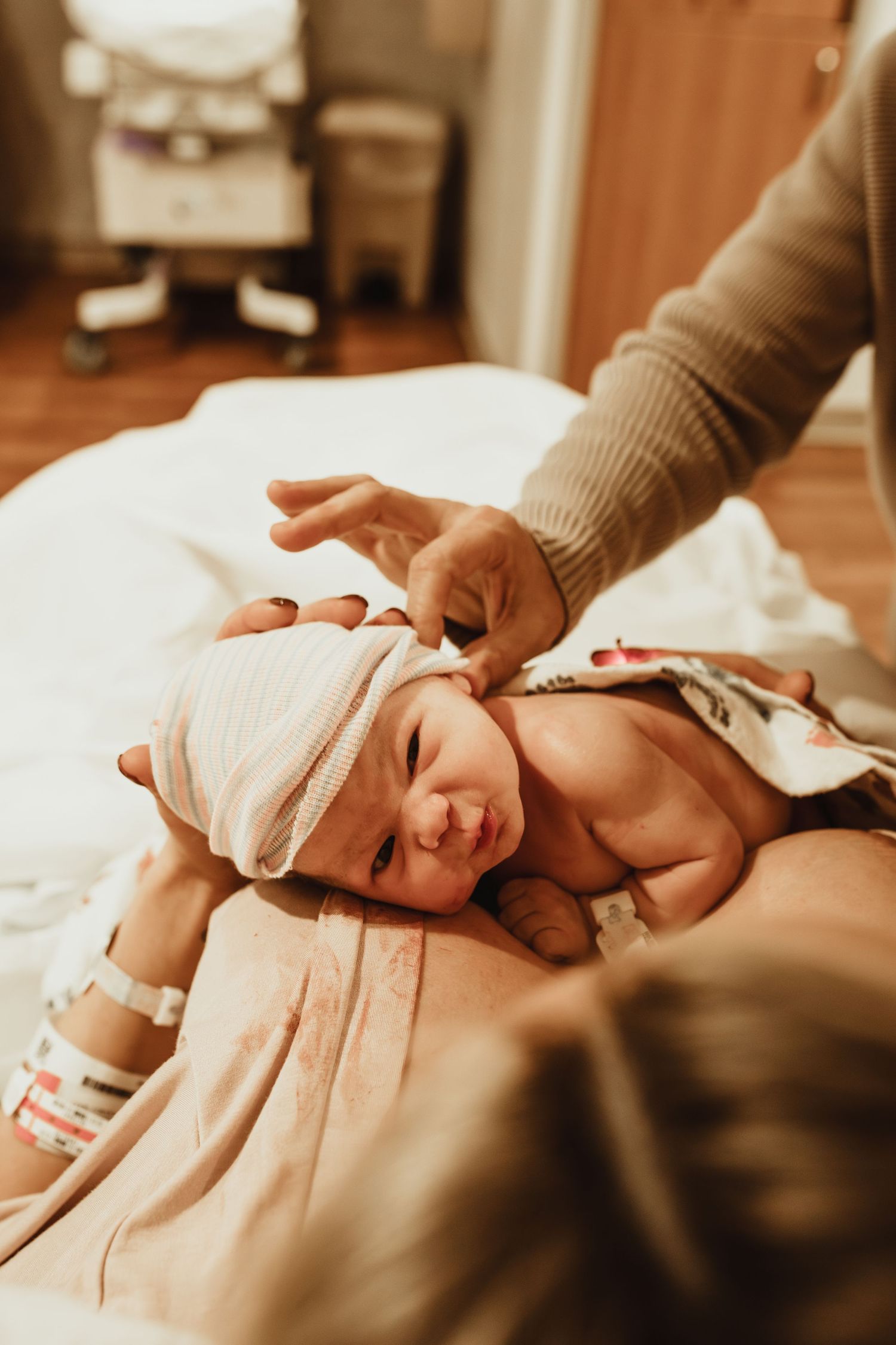 Gentle hands massage a newborn baby wrapped in soft white fabric during a spa treatment session.
