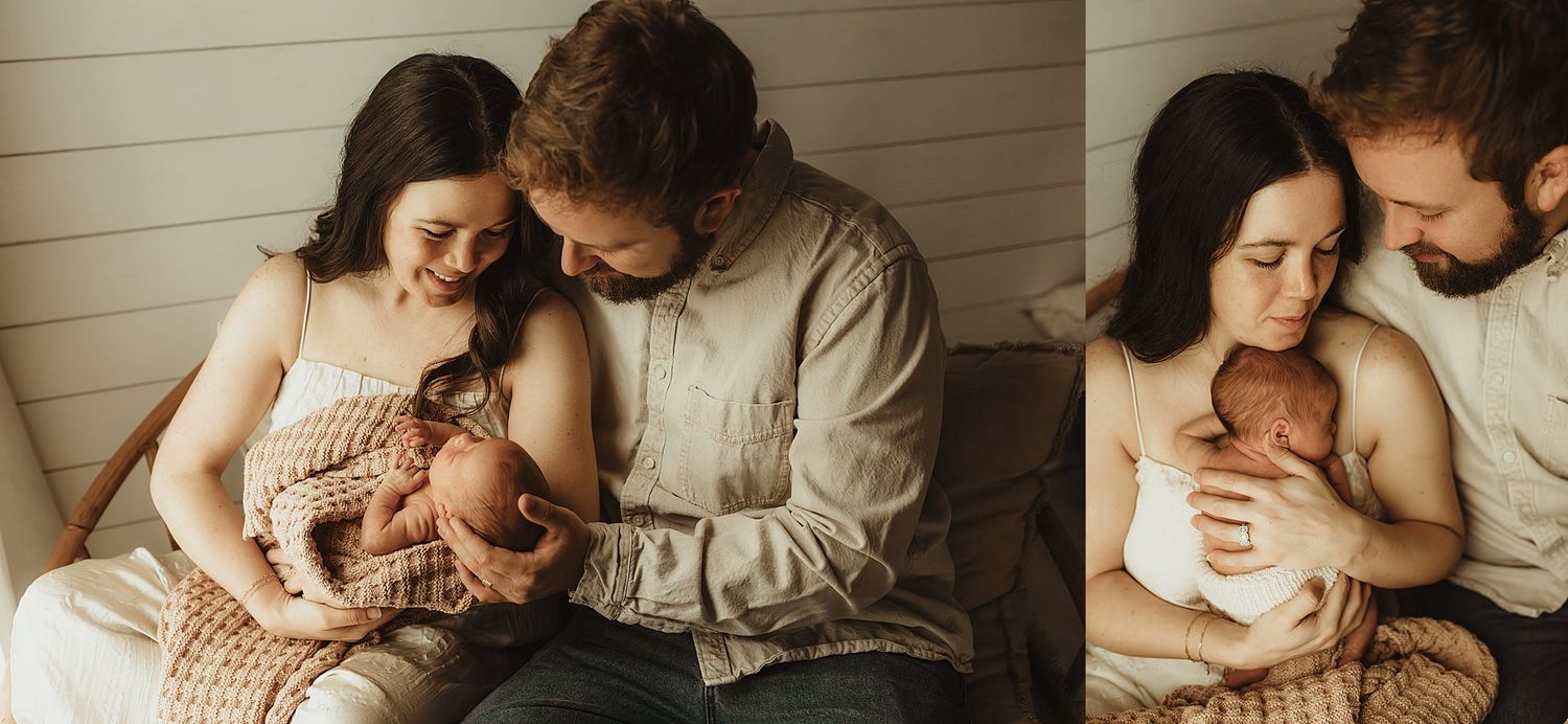 New parents tenderly cradle their newborn baby together, sharing a loving moment in a warm, softly lit studio setting.