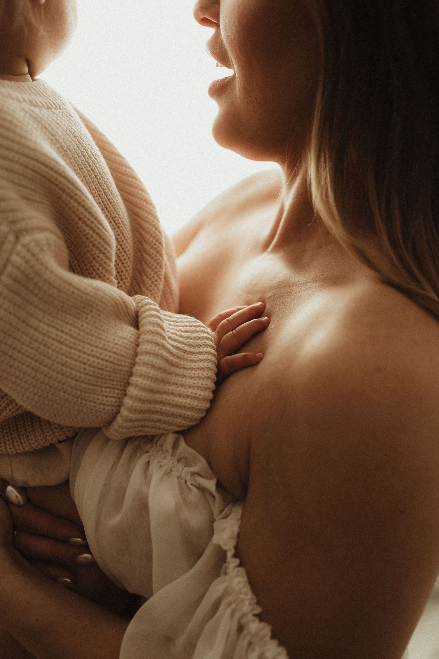 Close up details of a cream knit sweater and white fabric in warm ambient lighting.